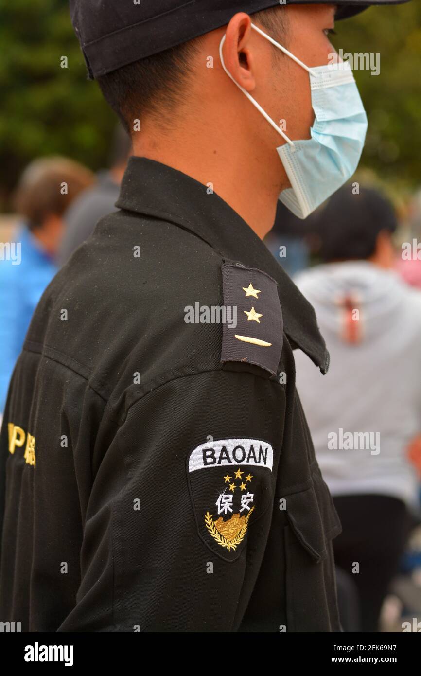 Un agent de sécurité portant un masque médical correctement installé surveille les personnes Dans un parc chinois Banque D'Images
