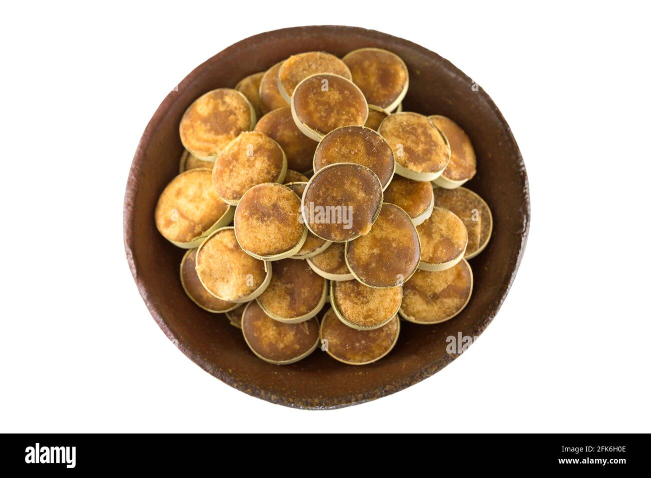 Bol en argile rempli de sucre de jaggery en palmier asiatique rempli de tranches de petites feuilles de palmier séchées, isolées sur fond blanc Banque D'Images