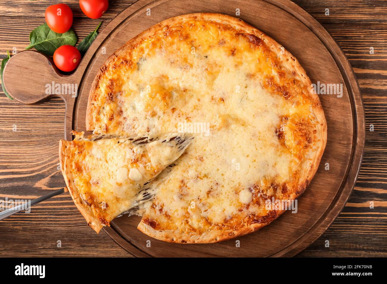 Prendre une tranche de pizza savoureuse à bord sur fond de bois Banque D'Images