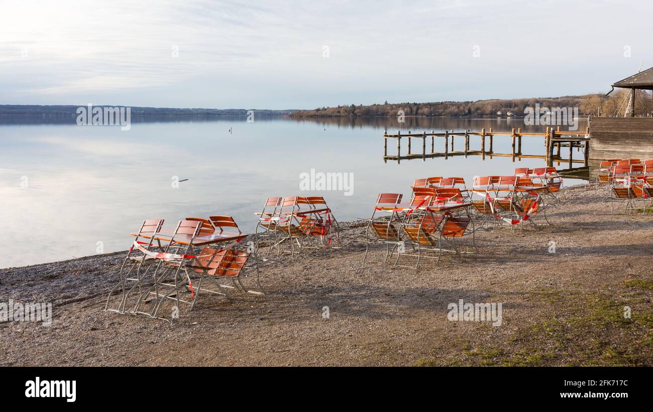 Herrsching, Allemagne - 4 février 2021: Chaises et tables d'un restaurant - fermé avec ruban barrière. Au bord du lac de Herrsching am Ammersee. Banque D'Images