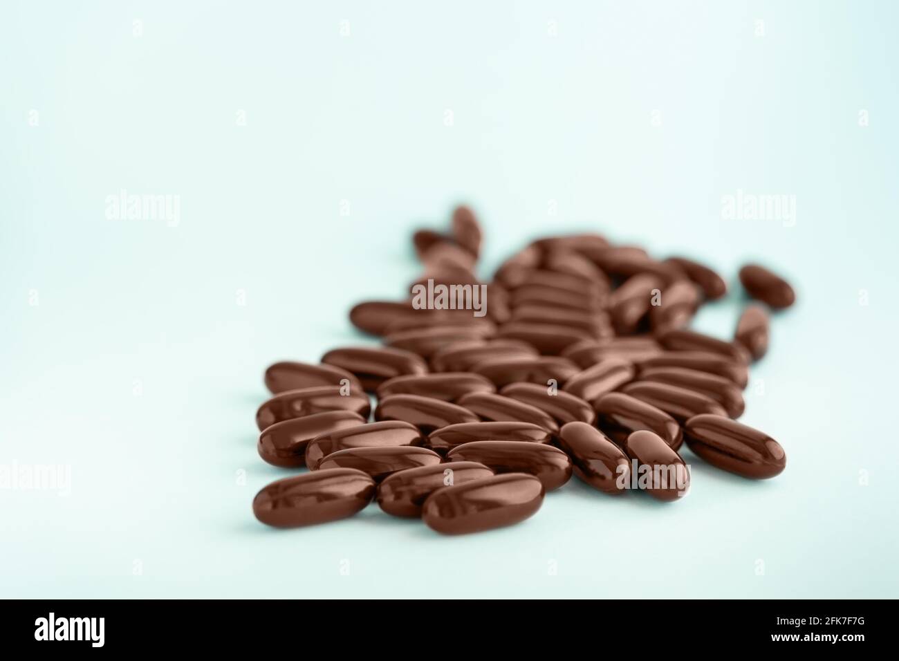 Capsules brunes, pilules gel avec huile isolées sur fond bleu. Compléments nutritionnels pour la perte de poids et l'énergie, aides alimentaires. Banque D'Images