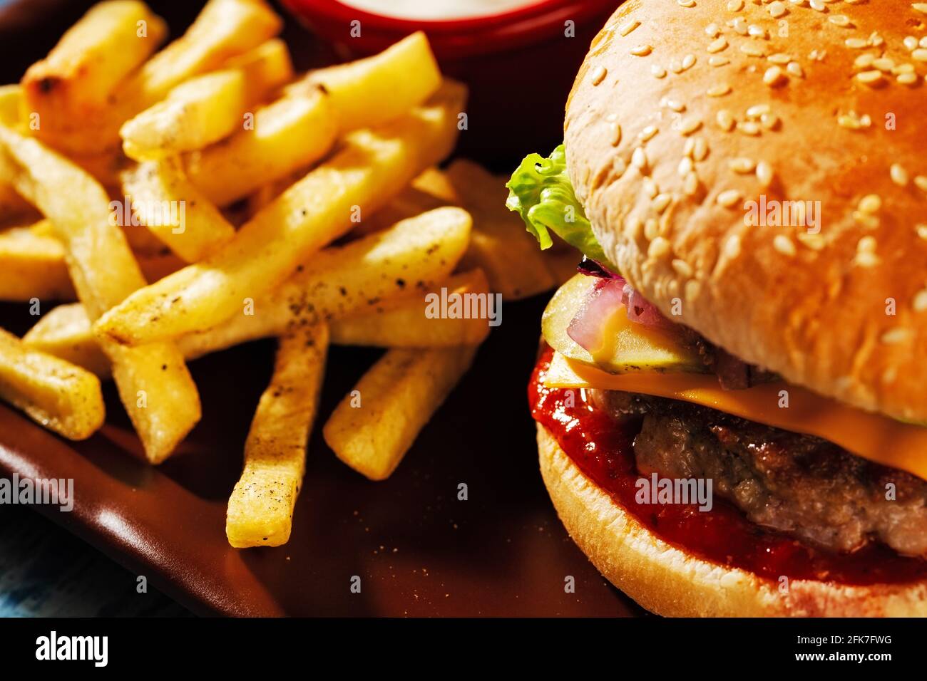 Hamburger. Côtelette de porc juteuse, cheddar, oignons croquants, laitue enveloppée dans un pain sous deux sauces. Servi avec des frites et de la sauce à la crème. Banque D'Images