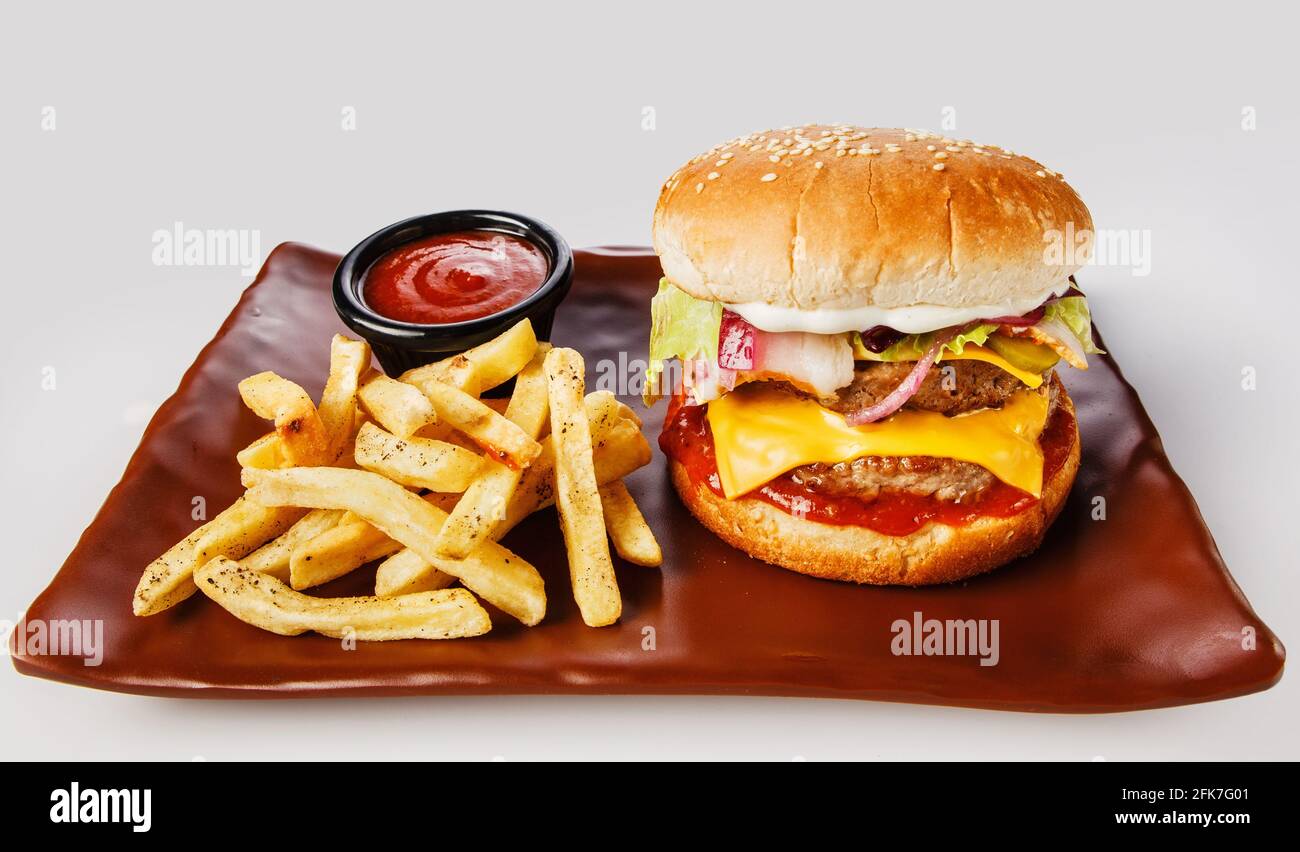 Hamburger. Côtelette de porc juteuse, cheddar, oignons croquants, laitue enveloppée dans un pain sous deux sauces. Servi avec des frites et de la sauce à la crème. Banque D'Images