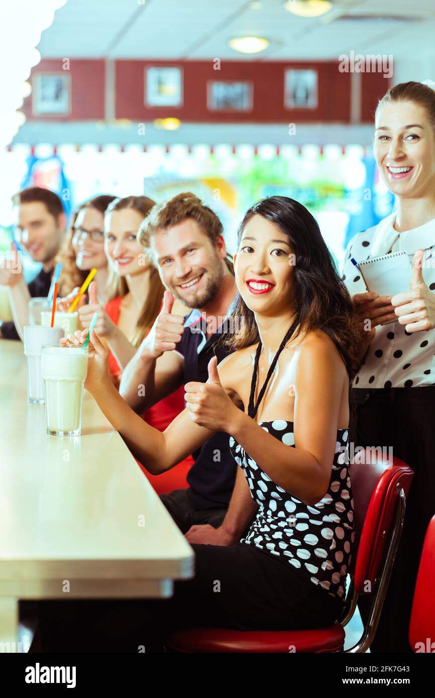 Des amis ou des couples eating fast food et de boire des milk-shakes sur bar en restauration rapide américaine diner, la serveuse est prise des commandes Banque D'Images