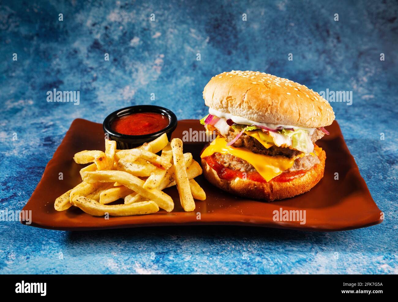 Hamburger. Côtelette de porc juteuse, cheddar, oignons croquants, laitue enveloppée dans un pain sous deux sauces. Servi avec des frites et de la sauce à la crème. Banque D'Images