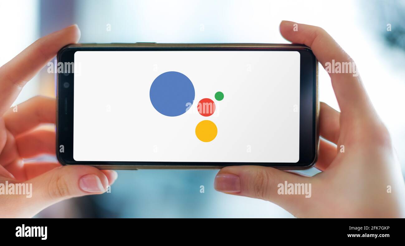 POZNAN, POL - APR 25, 2021: Mains tenant smartphone affichant le logo de Google Assistant, un assistant virtuel basé sur l'intelligence artificielle de développement Banque D'Images