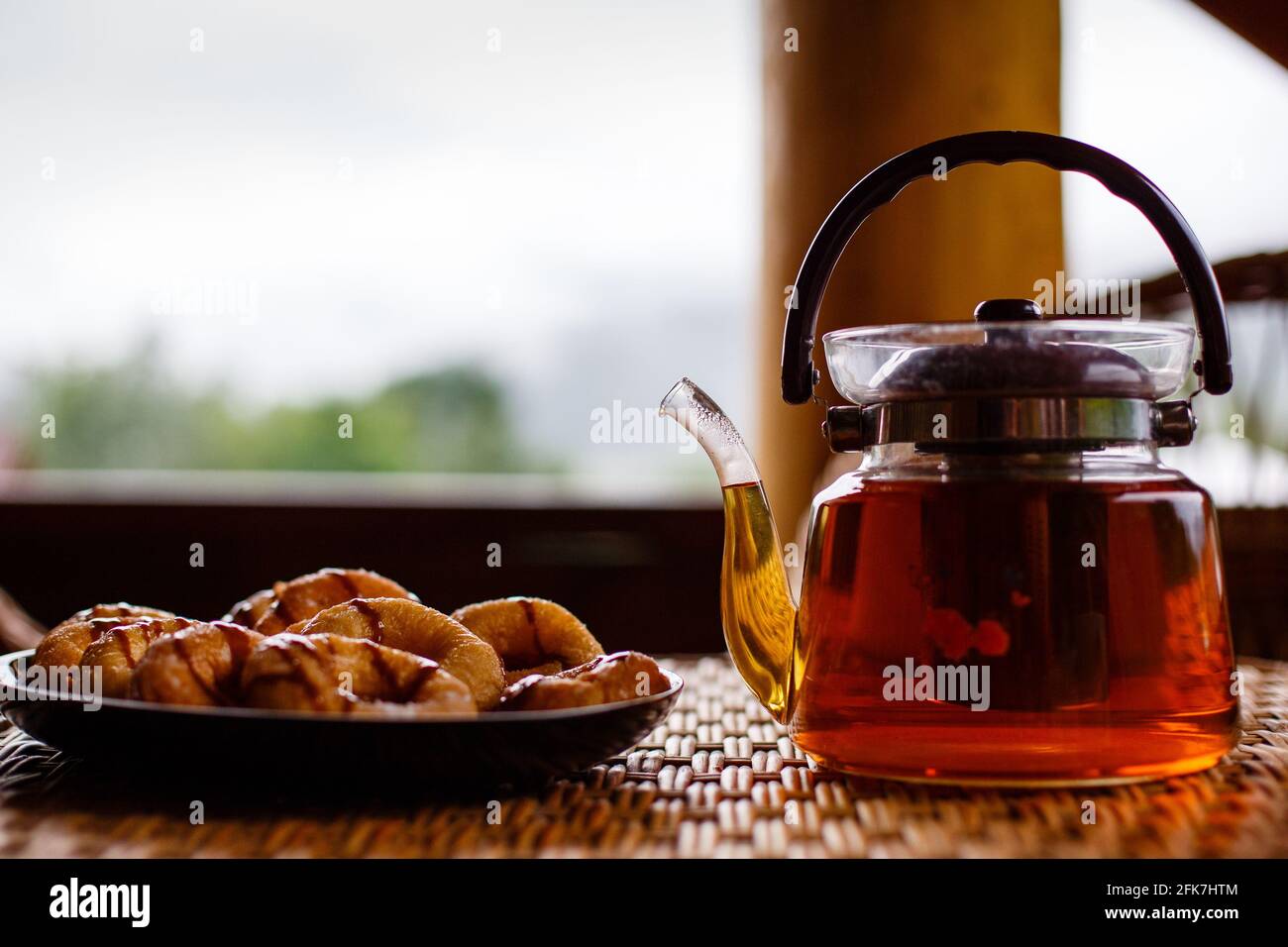 Gros plan de la théière en verre avec du thé aux herbes et des biscuits chauds sur la table. Banque D'Images