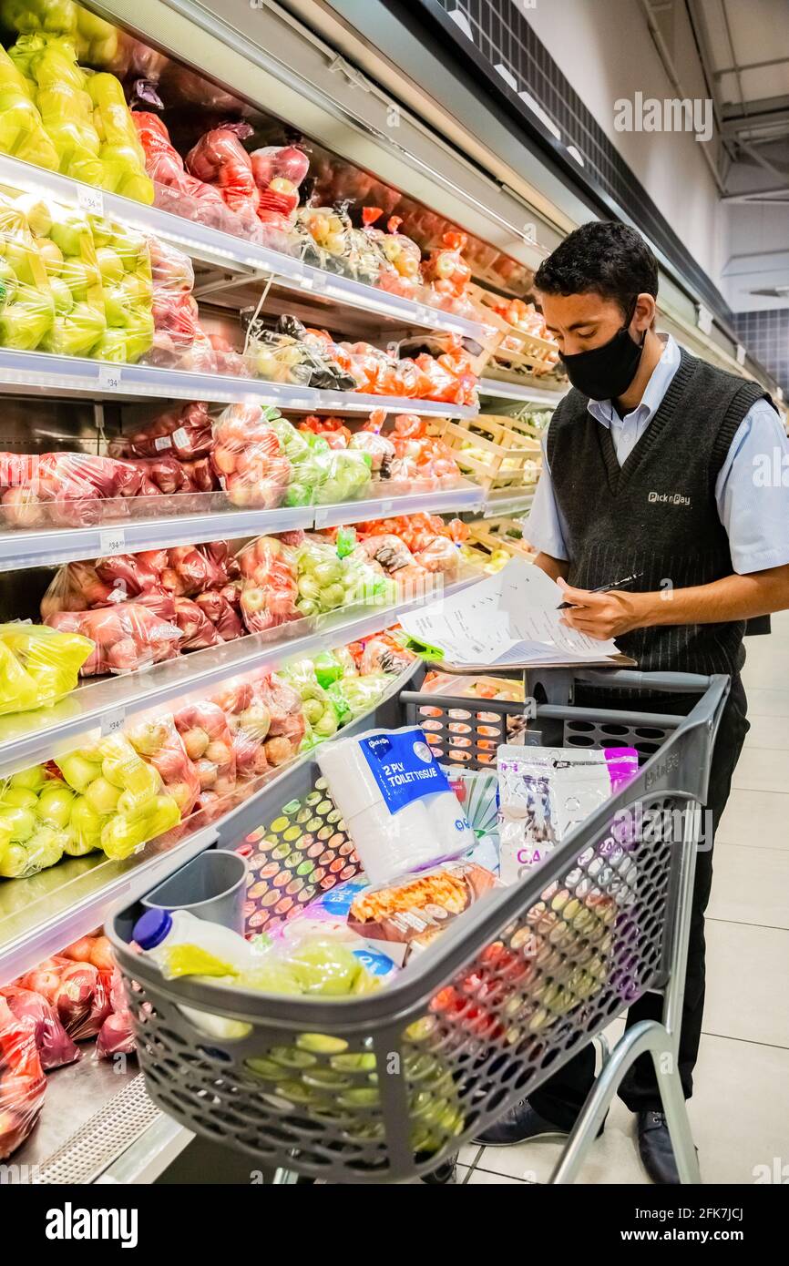 Cape Town, Afrique du Sud - 10 décembre 2020 : membre du personnel qui cueille les produits d'épicerie de l'étagère pour un service de livraison express à domicile au service local Pick n Pay su Banque D'Images