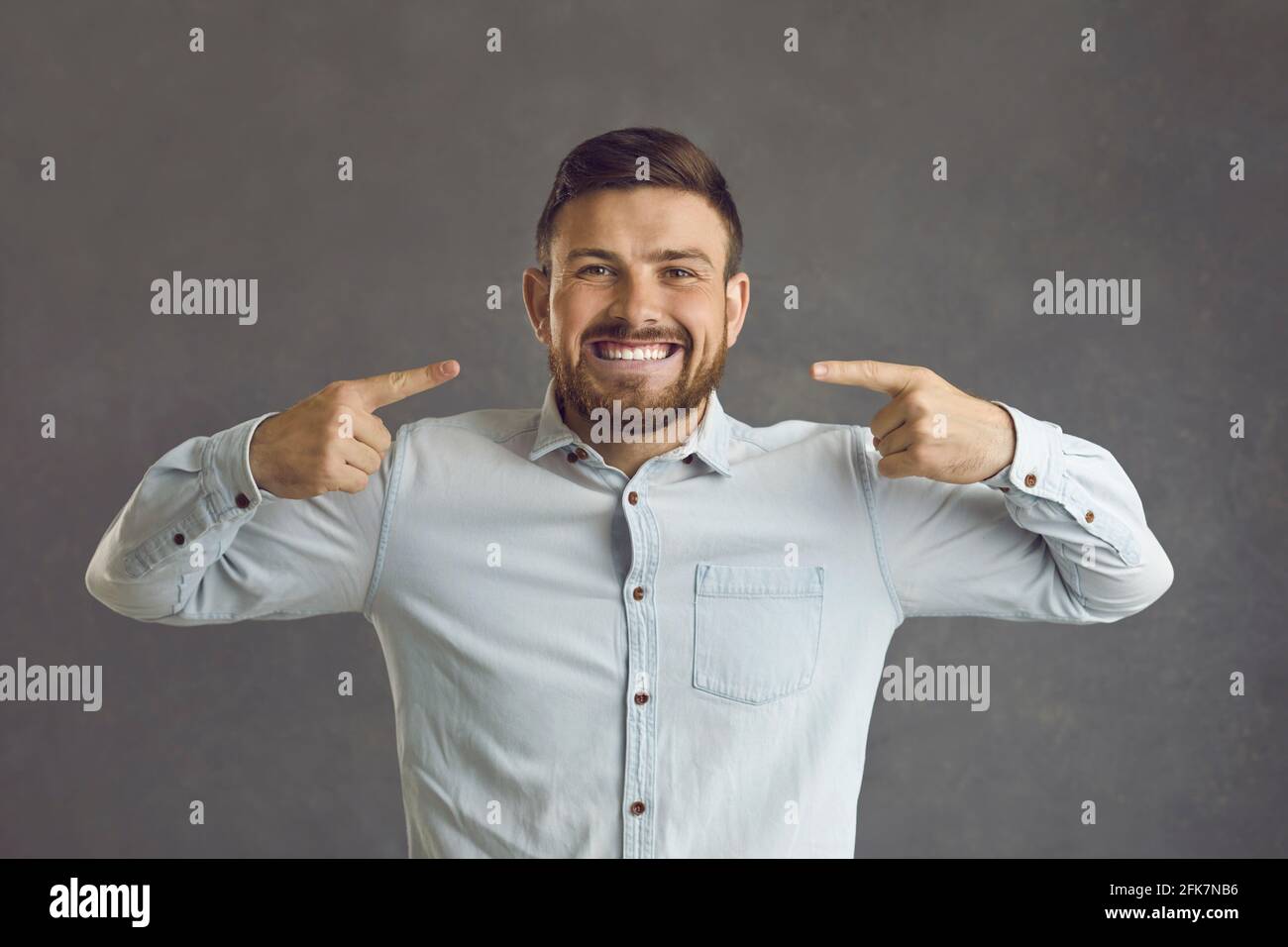 Portrait studio d'un jeune homme heureux pointant vers lui large sourire aux dents blanches parfaites Banque D'Images