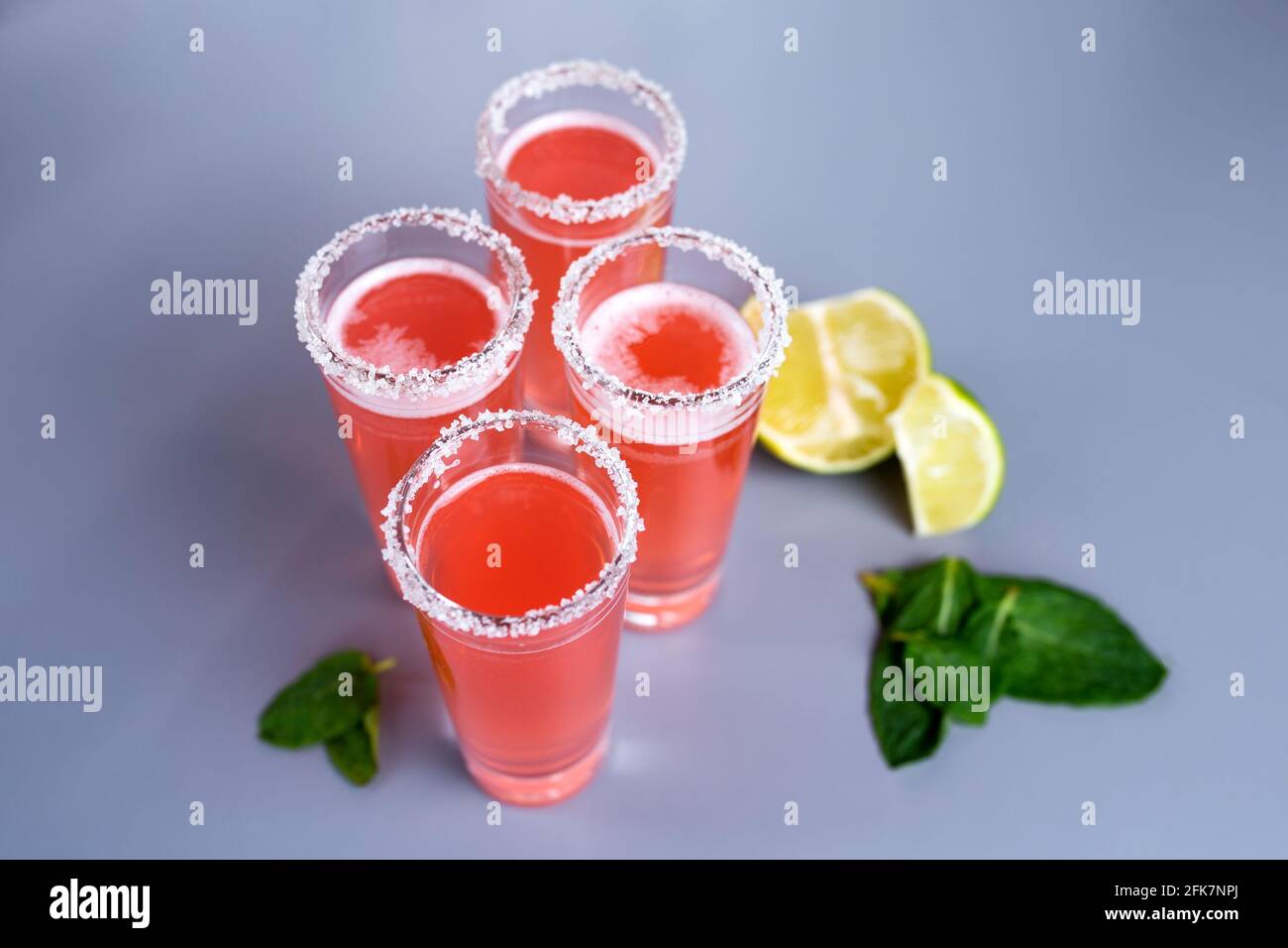 quatre cocktails roses avec vue sur le dessus de citron vert et menthe. Banque D'Images