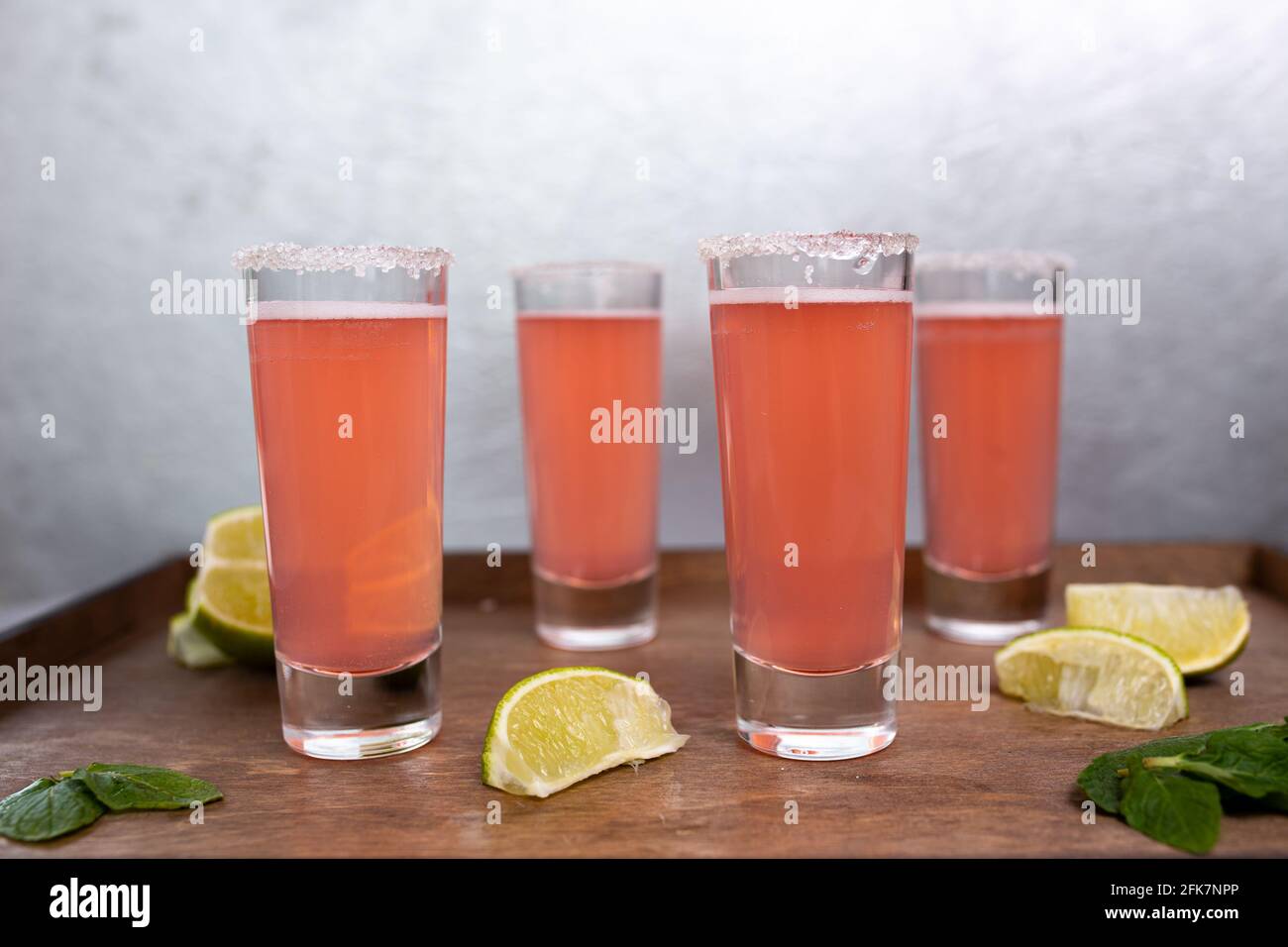 quatre cocktails roses avec des limes sur un stand en bois. Banque D'Images