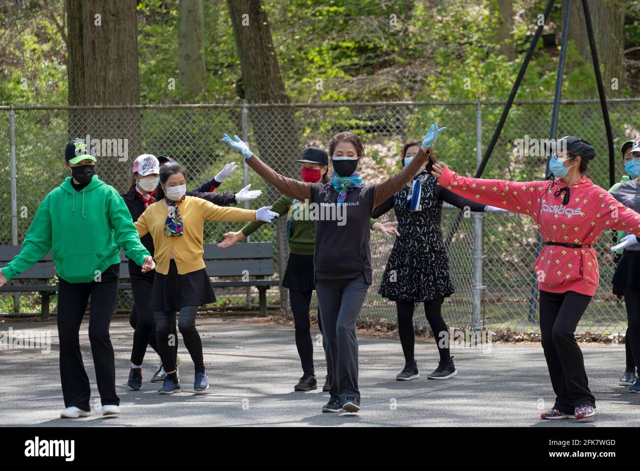Les femmes américaines chinoises gracieuses portant un masque répètent avec un groupe de danse dans un parc à Queens, New York, leur maître est dans le haut rouge Banque D'Images