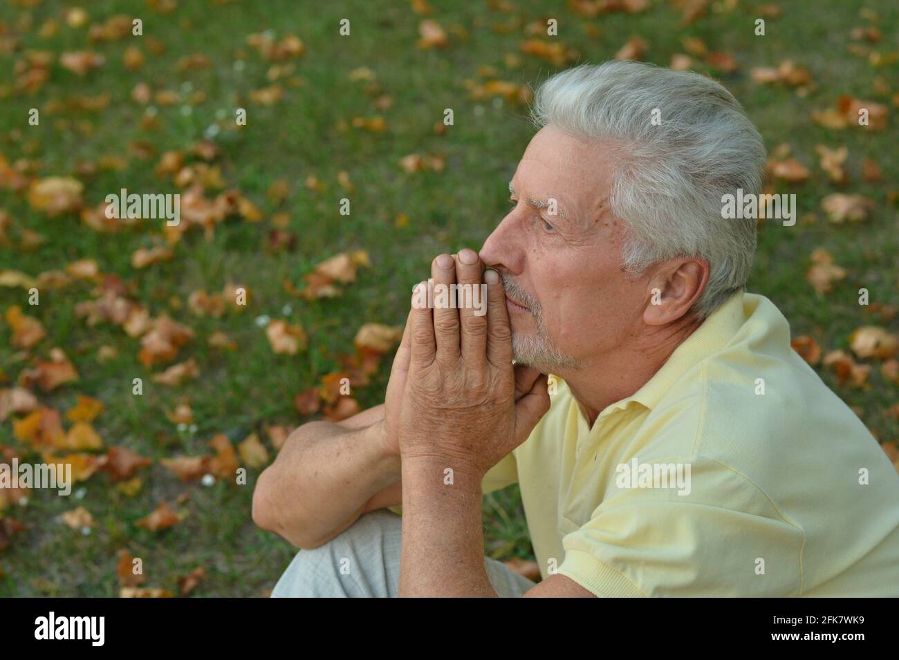 Portrait de l'homme âgé dans le parc assis sur l'herbe Banque D'Images