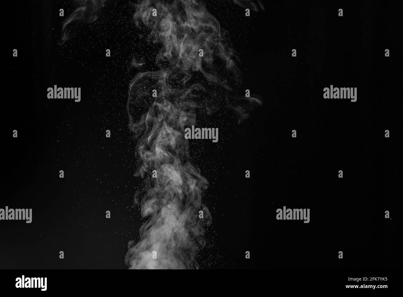 Vapeur blanche bouclés qui s'élève et projection d'eau dans différentes directions isolée sur fond noir. Évaporation du liquide et du condensateur Banque D'Images
