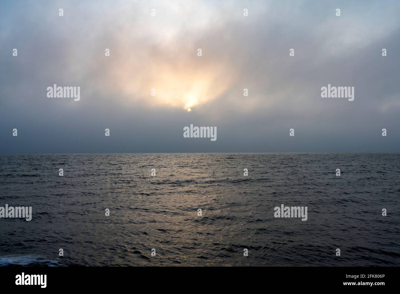 Soleil levant en partie caché derrière les nuages côtiers Banque D'Images