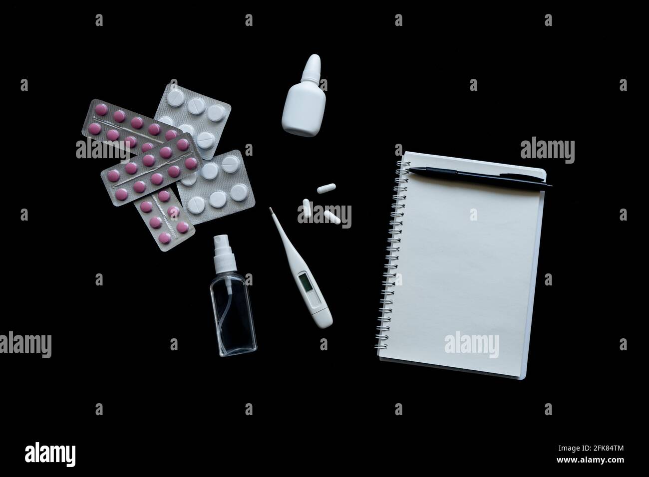 vue de dessus du thermomètre, des pilules et du carnet sur fond noir Banque D'Images