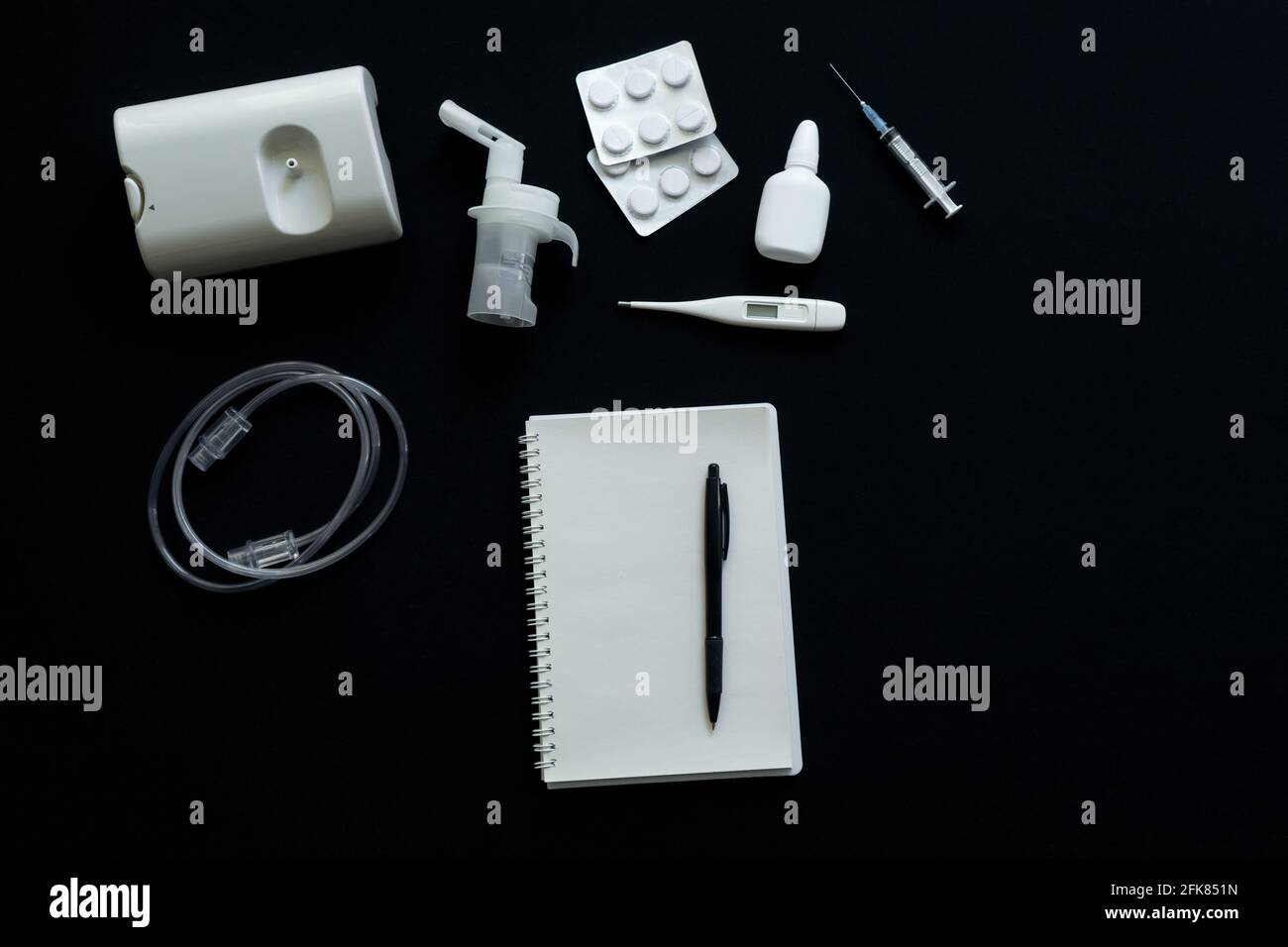 vue de dessus du nébuliseur, des pilules, du thermomètre et du carnet sur fond noir Banque D'Images