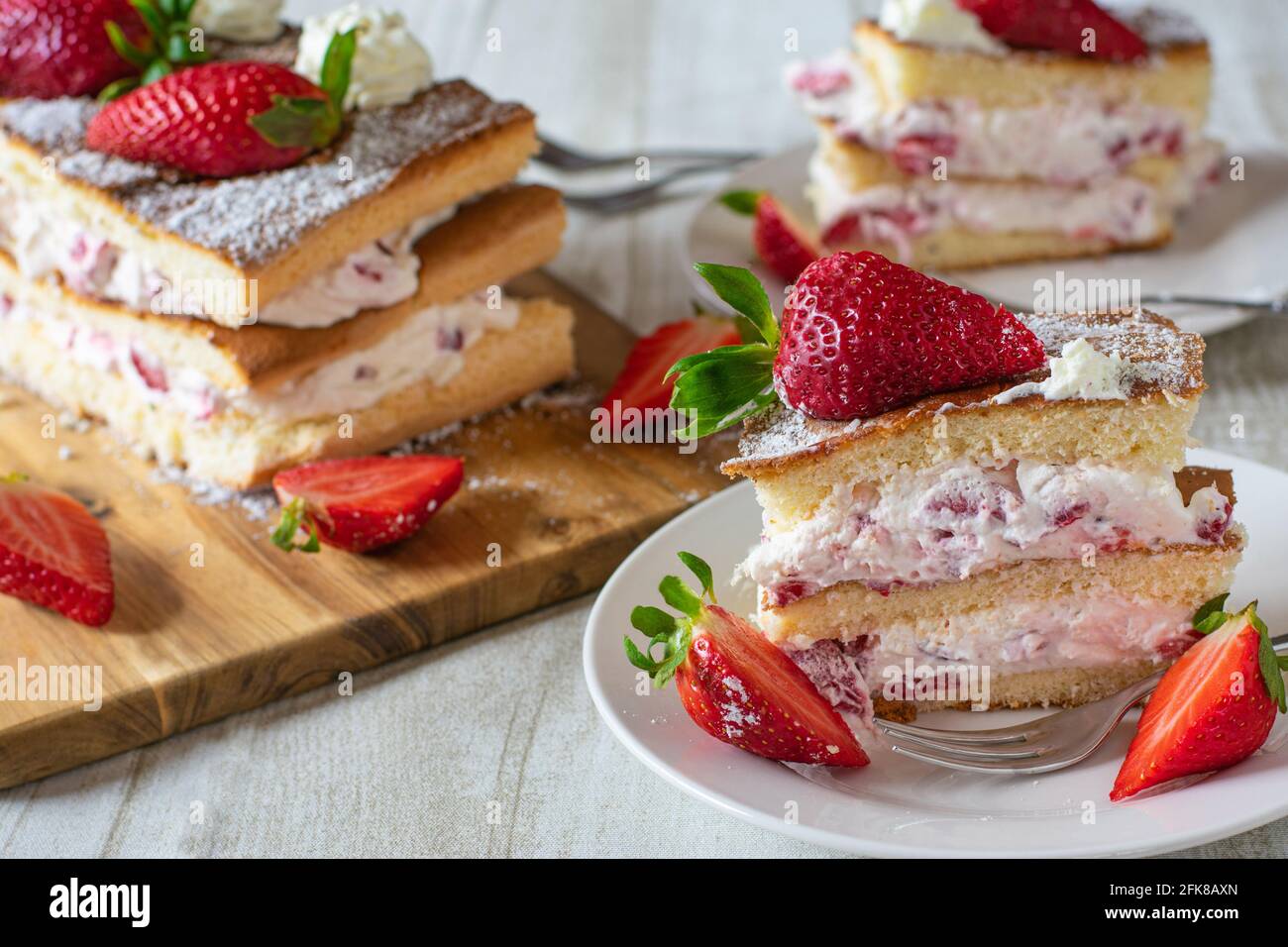 Un morceau de gâteau frais à la crème de fraise sur une assiette avec un fond rustique de table en bois Banque D'Images