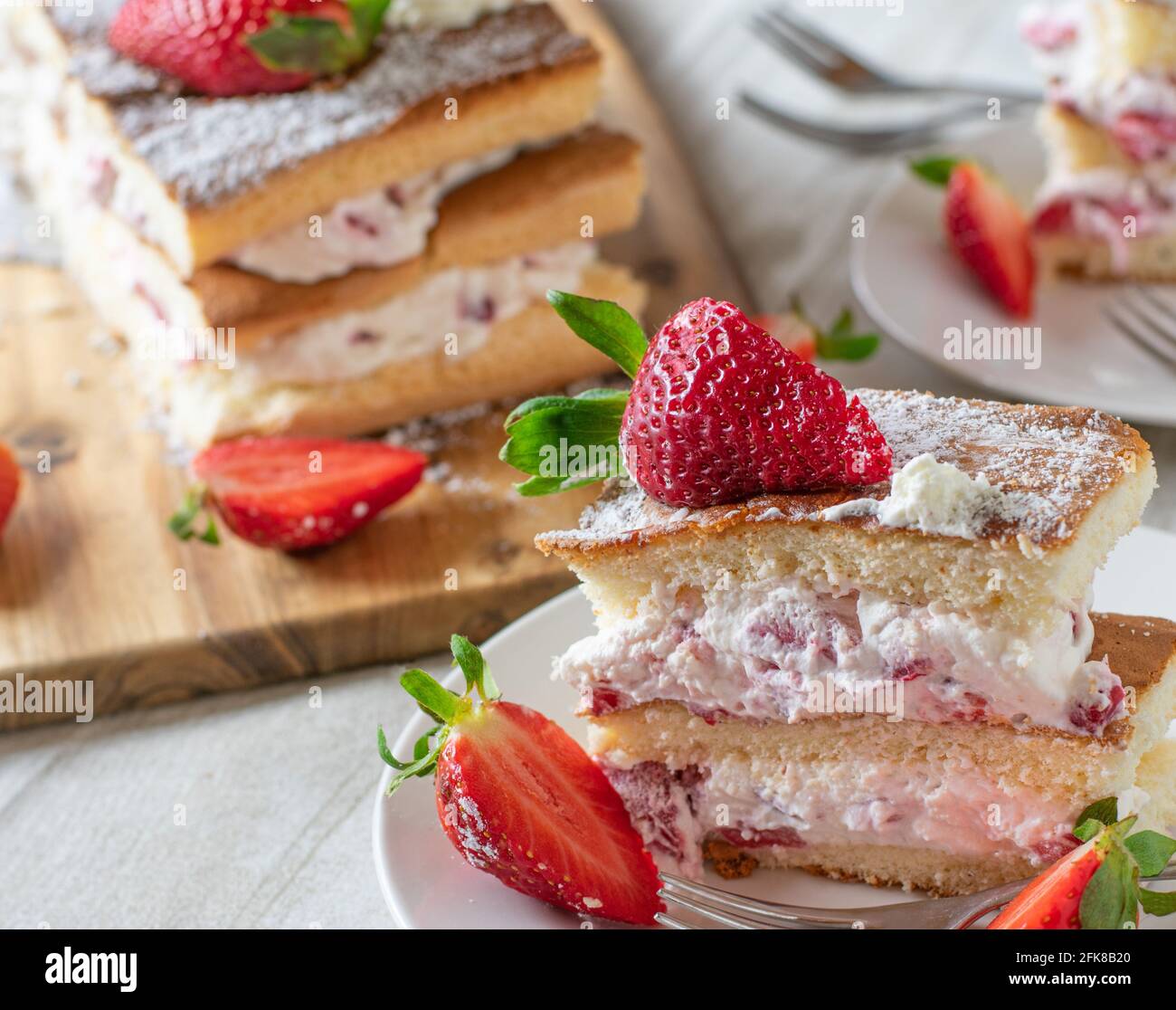 Un morceau de gâteau frais à la crème de fraise sur une assiette avec un fond rustique de table en bois Banque D'Images