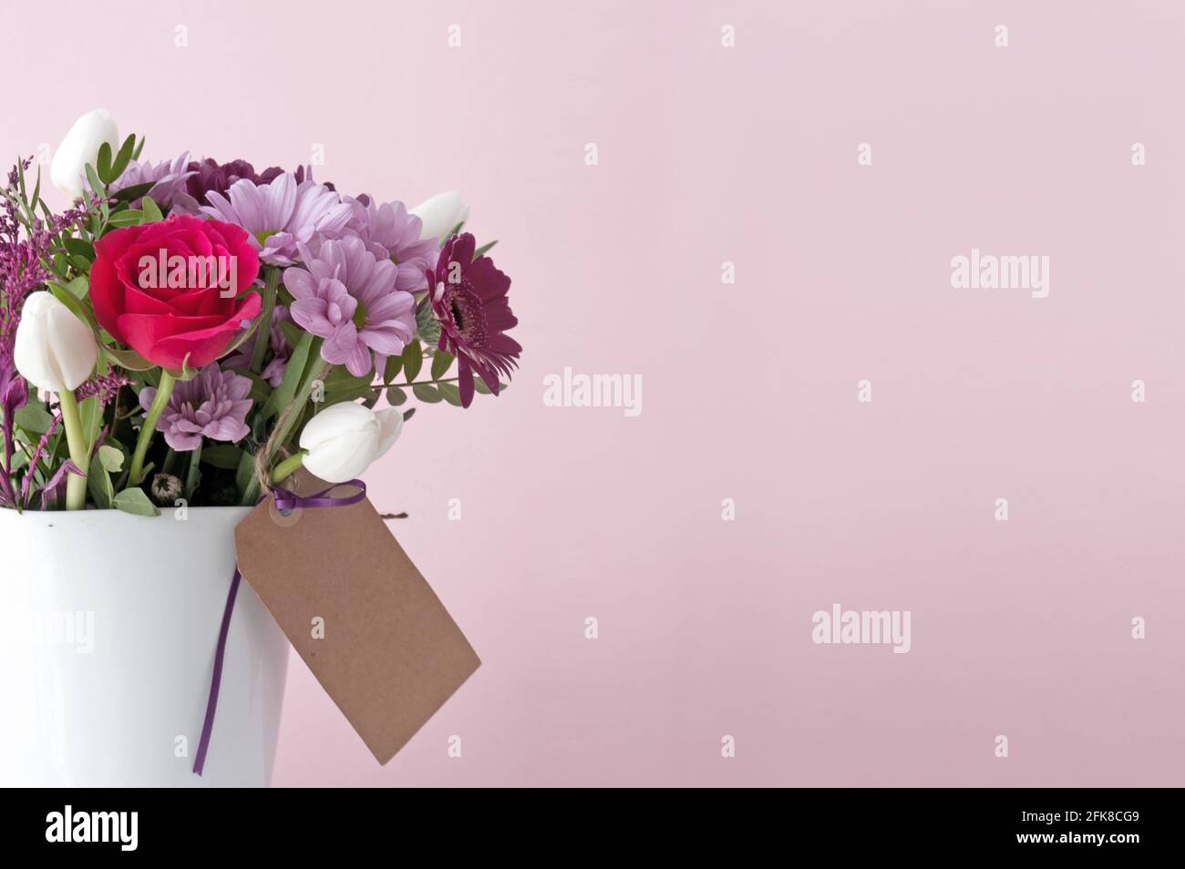 Bouquet de fleurs cadeau dans un vase blanc et étiquette vide Banque D'Images