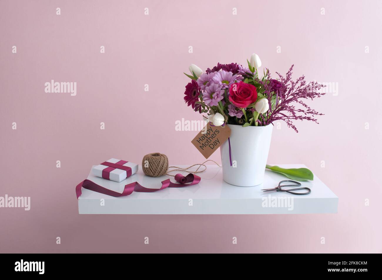 Fleurs de fête des mères avec carte de vœux sur une étagère blanche flottante, arrière-plan design intérieur Banque D'Images