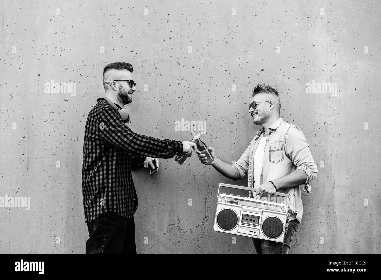 Un couple gay boit de la bière en plein air tout en écoutant de la musique avec un Lecteur de cassettes boombox vintage - les gars de taille basse fêtent leur amitié pendant nous Banque D'Images