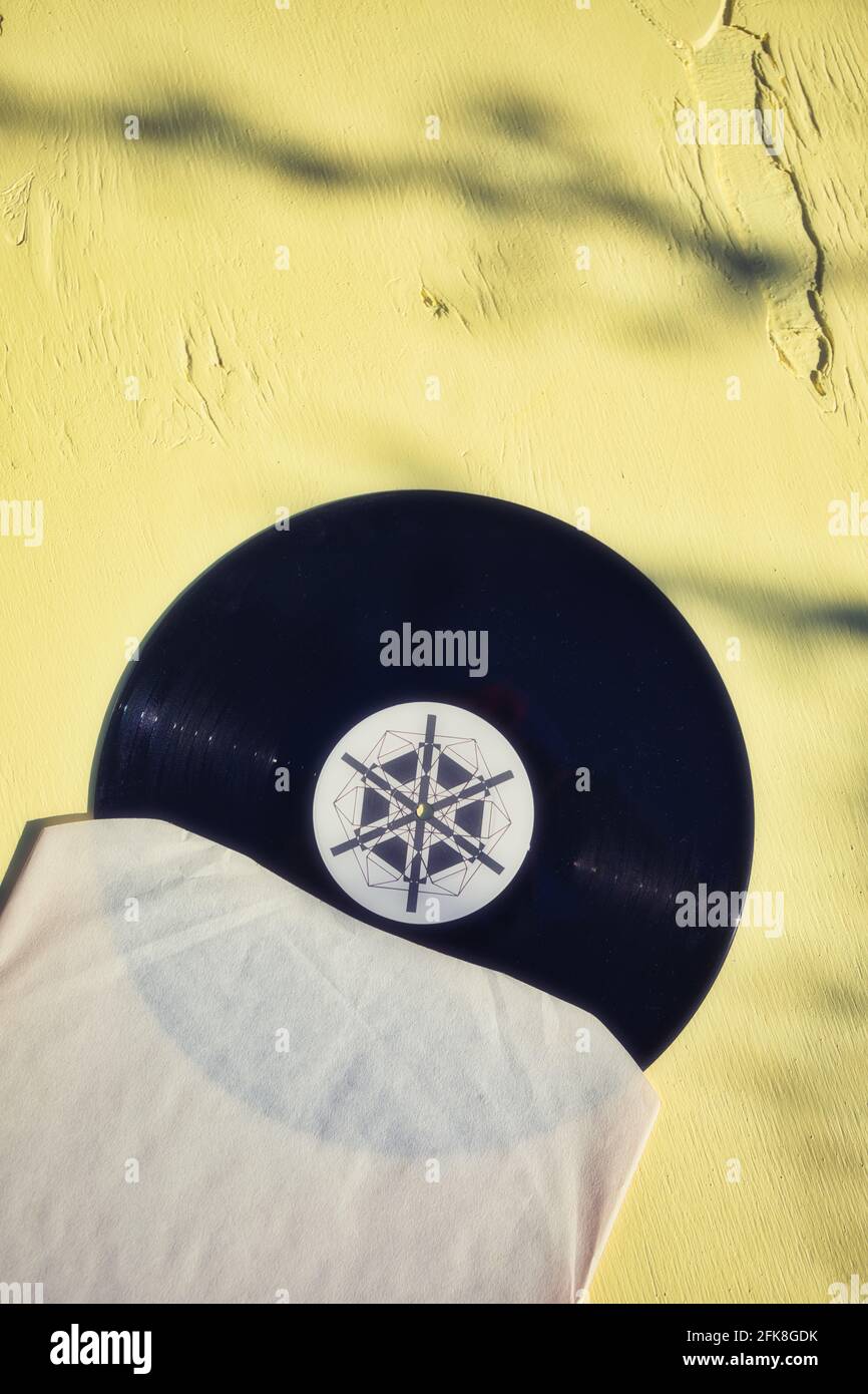 Directement au-dessus de 12 pouces LP vinyle record sur fond jaune en bois dans la lumière du soleil et l'ombre. Concept de rétro, nostalgie, antan, vintage Banque D'Images