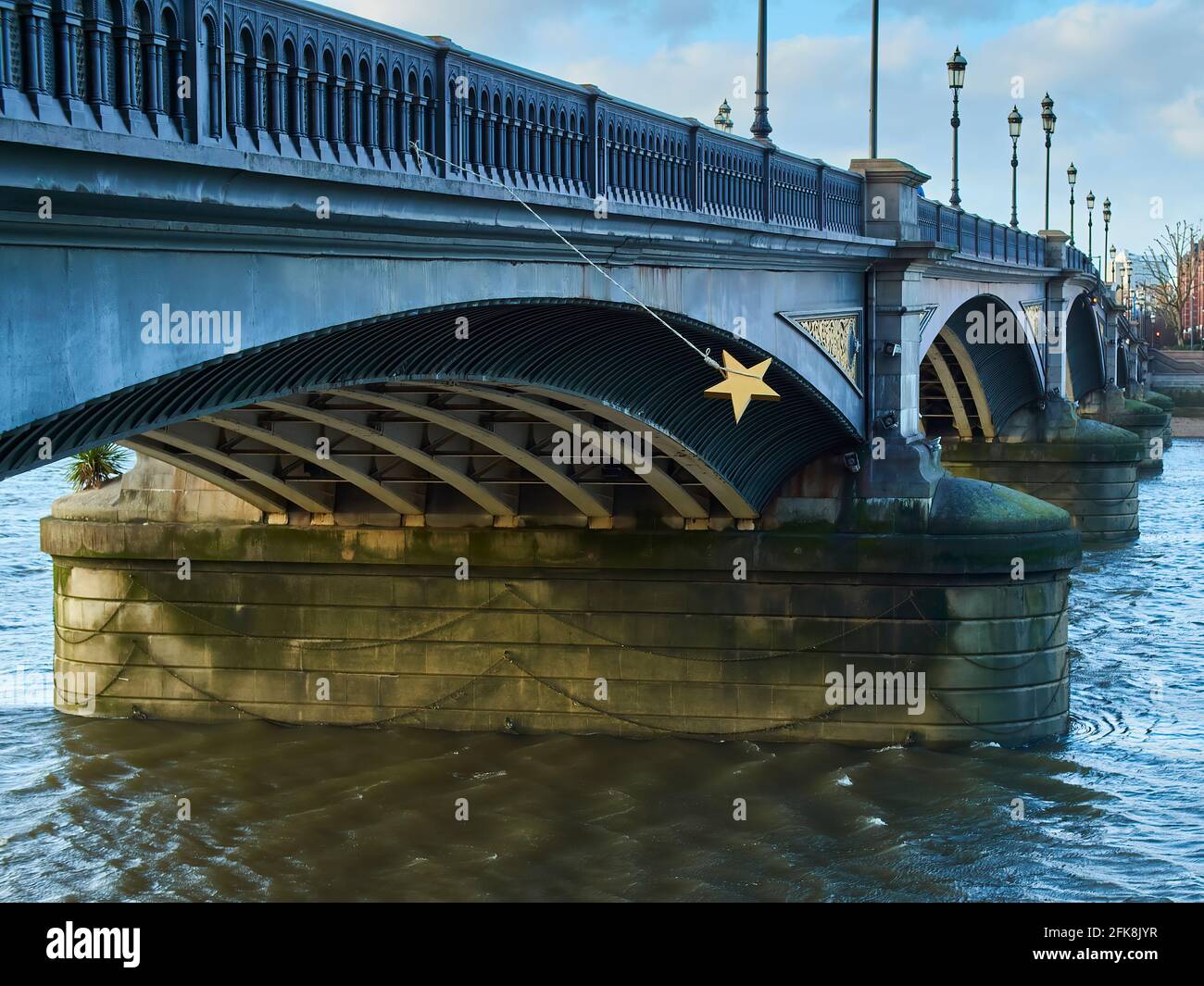 Une étoile d'or se balançant dans le vent depuis une corde attachée au pont de Battersea, sous un soleil d'hiver lumineux et à faible angle. Banque D'Images