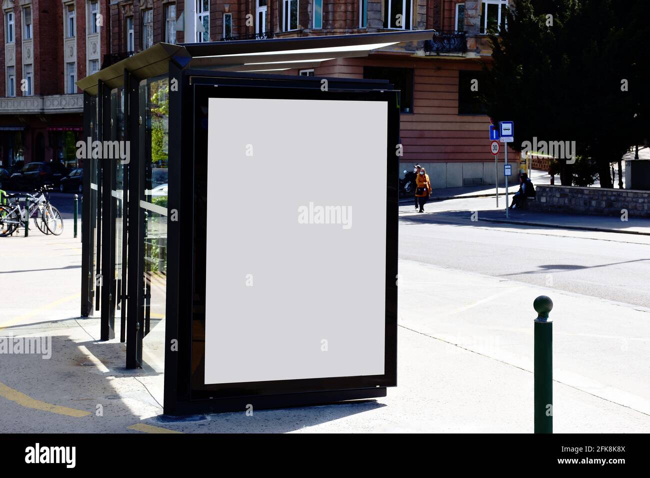 abri de bus. arrêt de transit. visionneuse blanche vierge. structure en verre. cadre urbain. rue de la ville. trottoir en asphalte. affiche et espace commercial vide. Banque D'Images