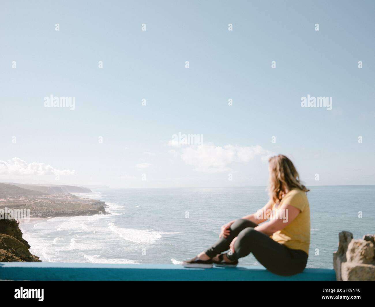 Femme pas dans le foyer en regardant sur la baie à Ericeira Portugal Europe. Photographie de voyage aventureuse Banque D'Images