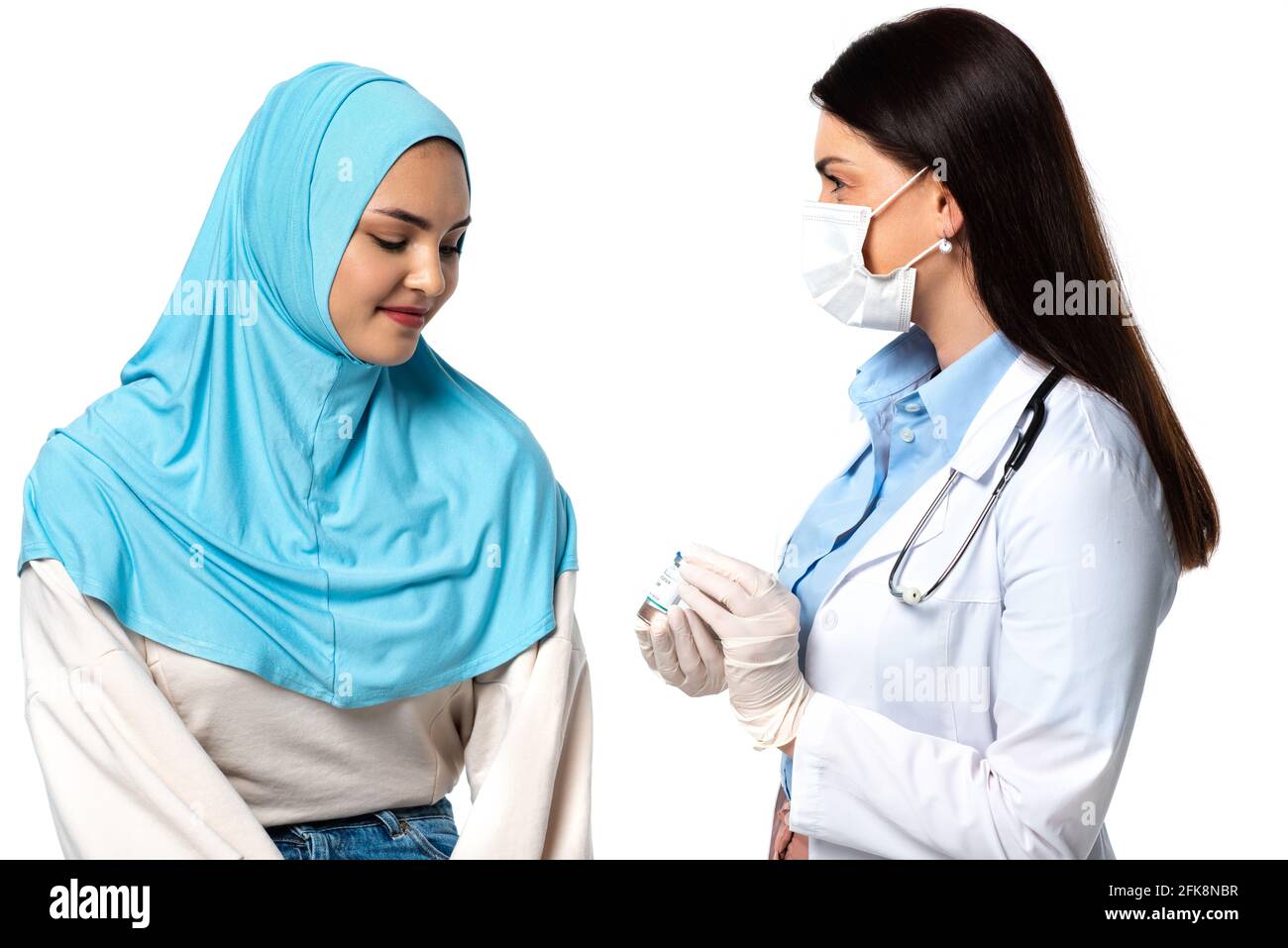 Médecin dans un masque médical tenant le vaccin près d'un patient arabe isolé sur blanc Banque D'Images