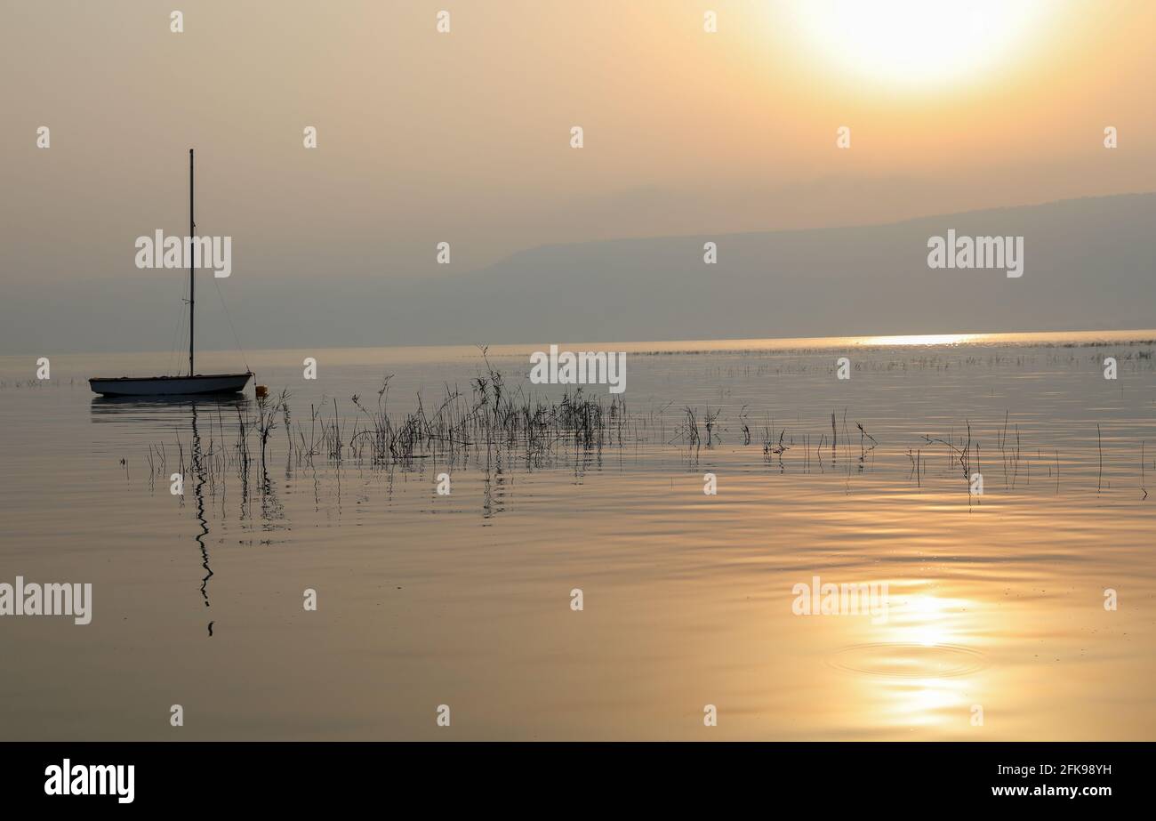 Lever du soleil sur le lac. Bateau flottant sur l'eau calme sous un coucher de soleil étonnant. Banque D'Images