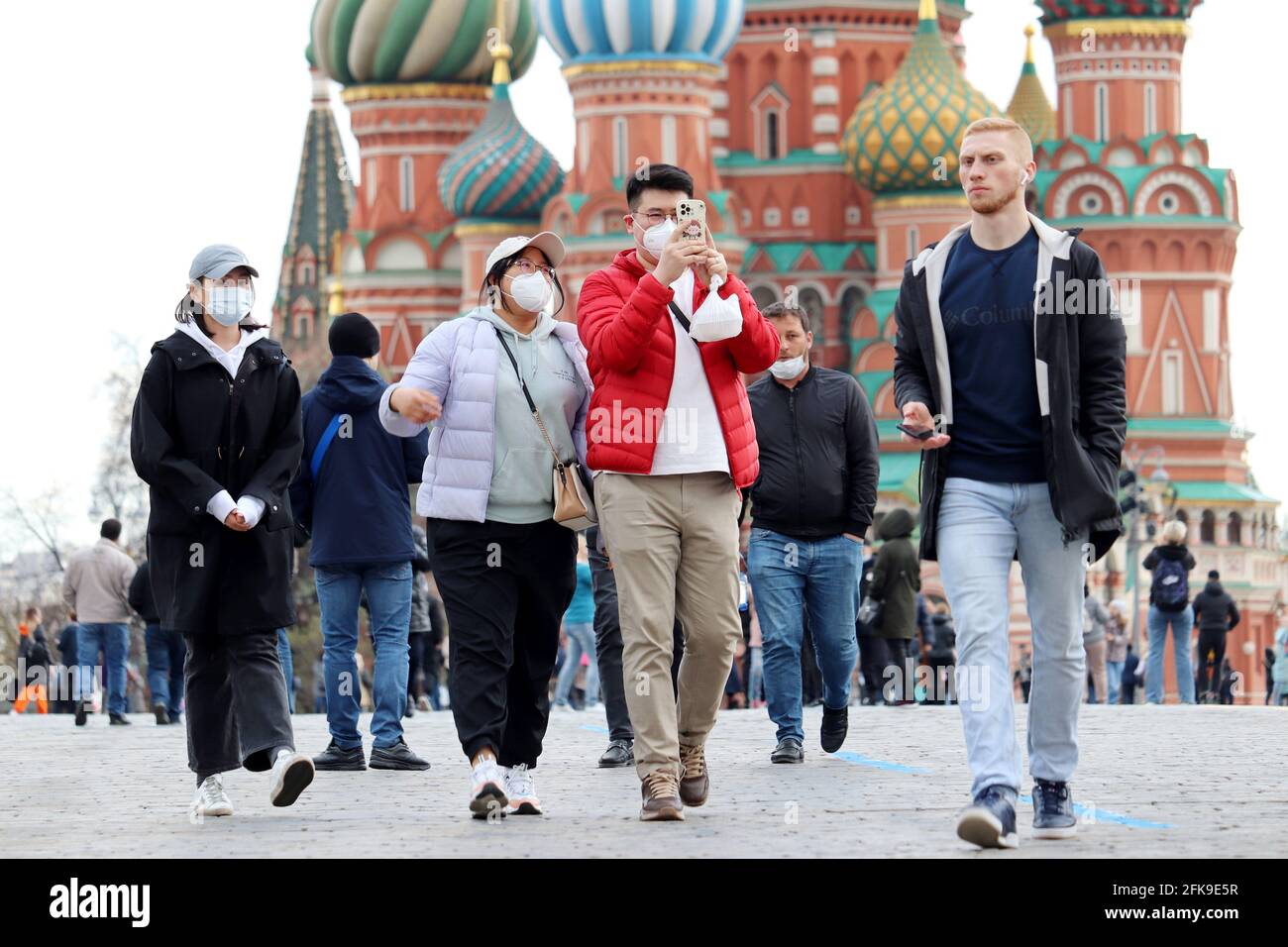 Les touristes asiatiques dans des masques médicaux protecteurs marchant sur un rouge Place à Moscou sur fond de la cathédrale de Saints Basile Banque D'Images