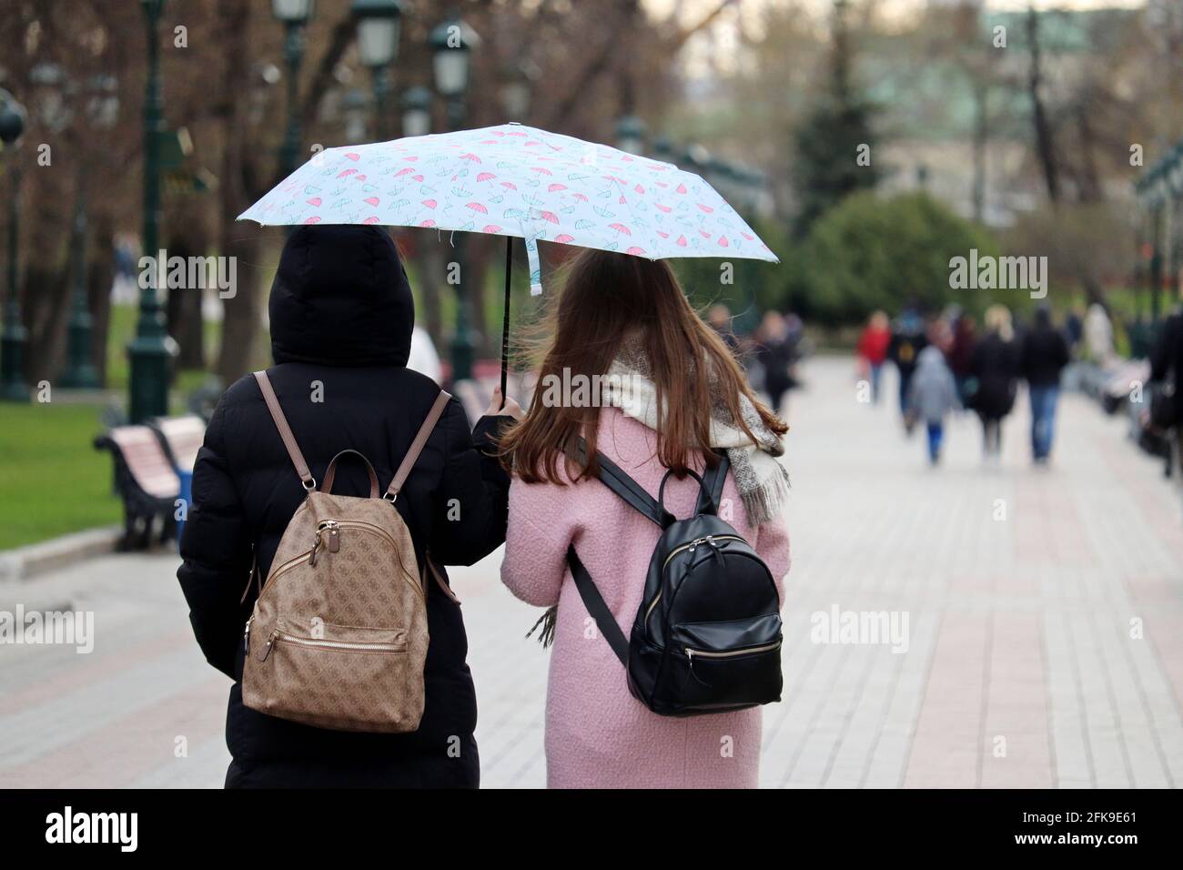 Pluie en ville, deux filles avec un parasol marcher sur une rue sur le fond des gens. Temps pluvieux, tempête printanière Banque D'Images