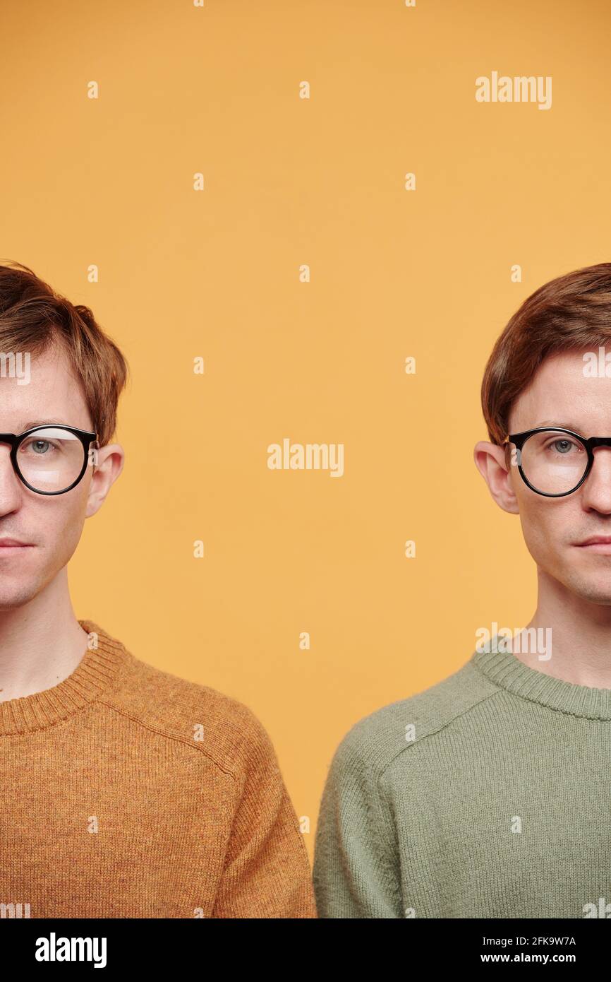 Demi-visages de jumeaux en lunettes et pulls brillants debout sur fond orange Banque D'Images