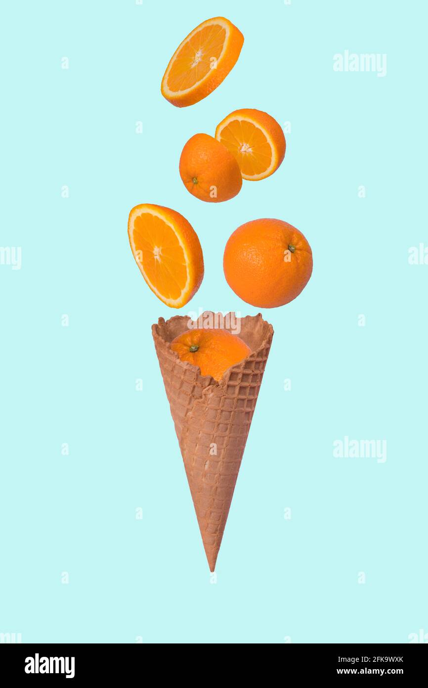 Idée minimale avec un cône de crème glacée et une tranche d'orange fraîche sur fond bleu pastel. Concept minimal de fruits d'été.vitamines, concept de régime sain. Coupe Banque D'Images