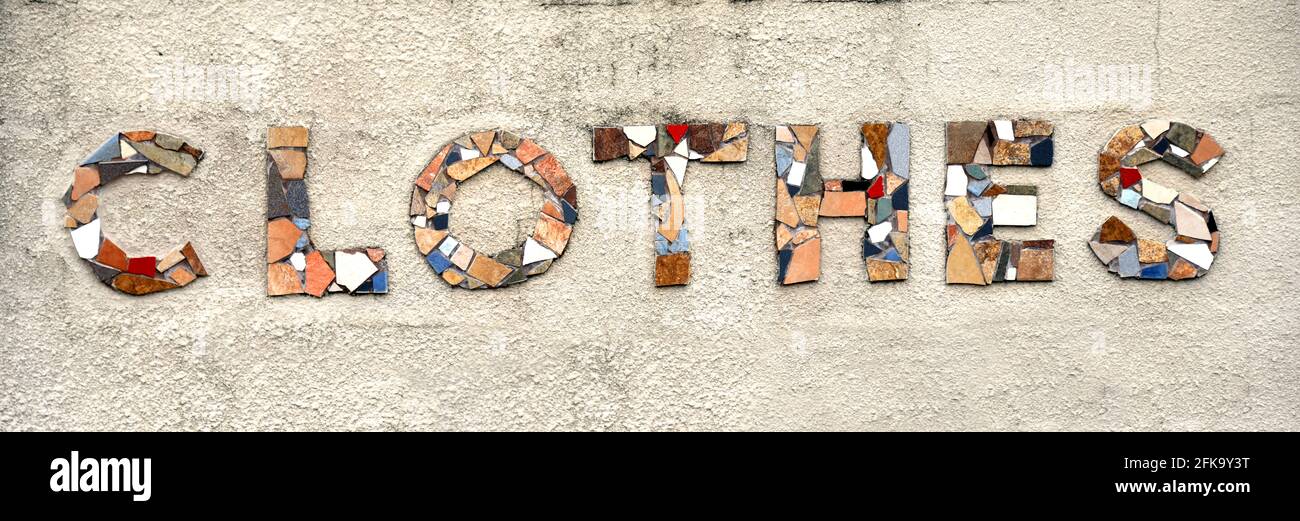 Le mot habits est formé de morceaux de carreaux cassés. Les lettres sont montées sur un mur en béton. Banque D'Images