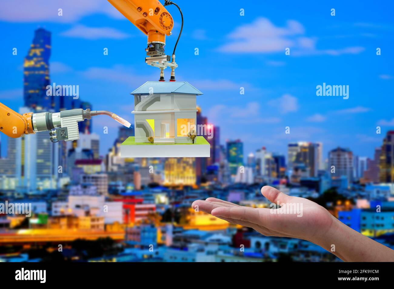 Gros plan robotique industrielle travaillant avec la maquette domestique pour homme d'envoi à main sur fond bleu foncé paysage urbain, concept de l'industrie 4.0 Banque D'Images