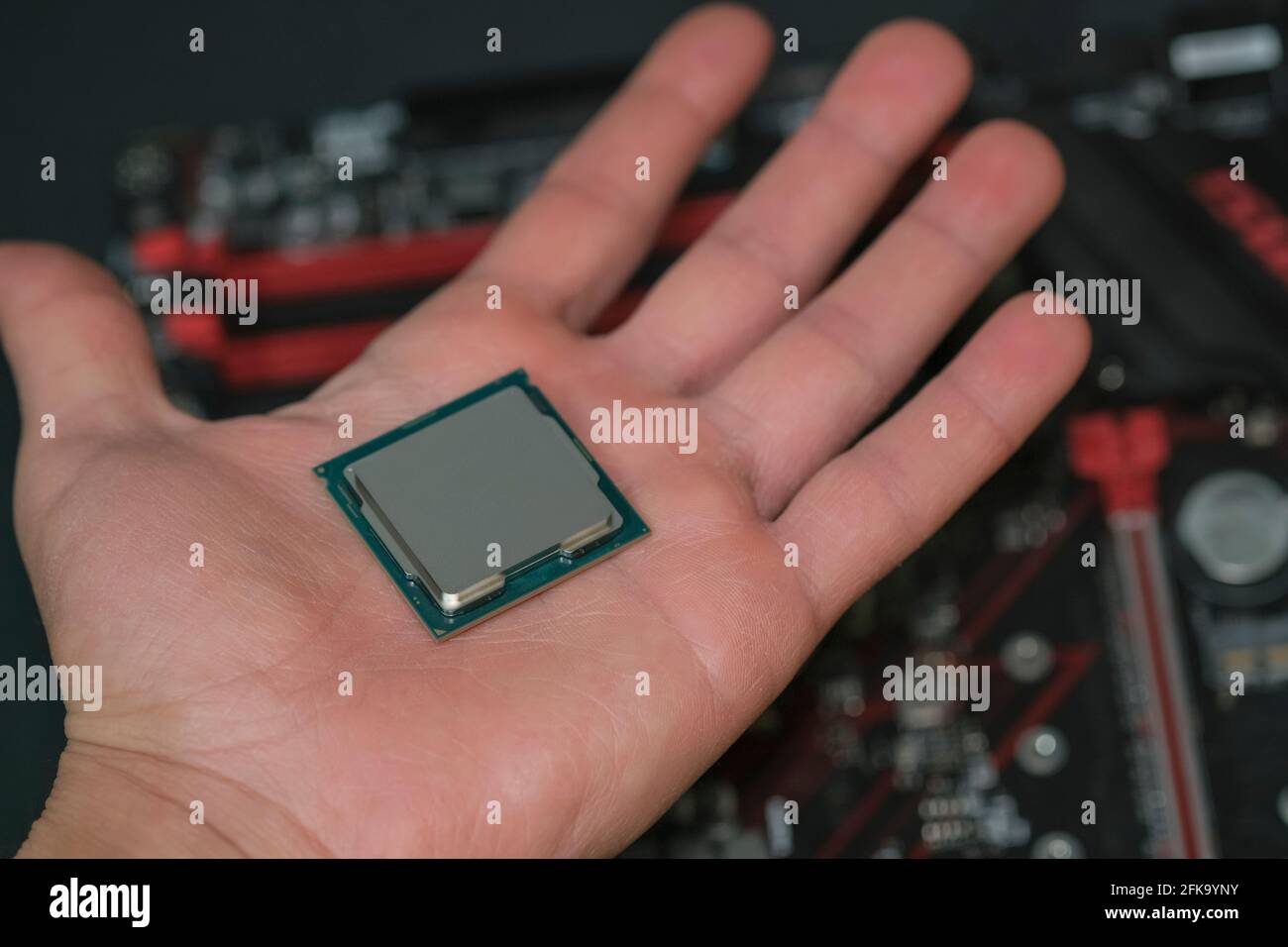 Homme main tenir le processeur de PC de bureau par rapport à la haute technologie carte mère, puce des composants de l'ordinateur Banque D'Images