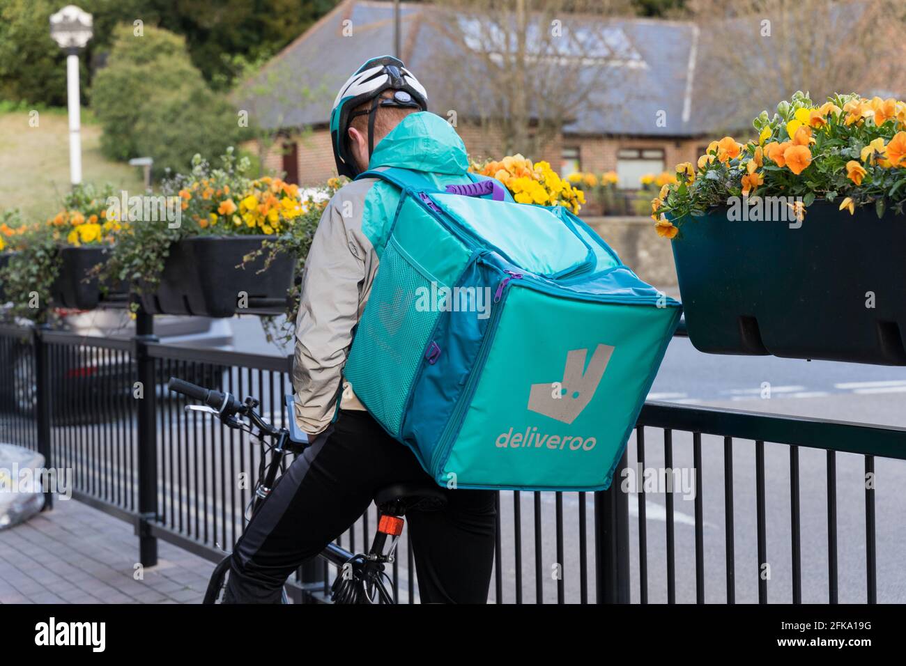 Deliveroo Biker vérifie son mobile pour la direction de l'adresse du client sur le pillage par les rails de fer avec panier de fleurs suspendu, Kent Banque D'Images