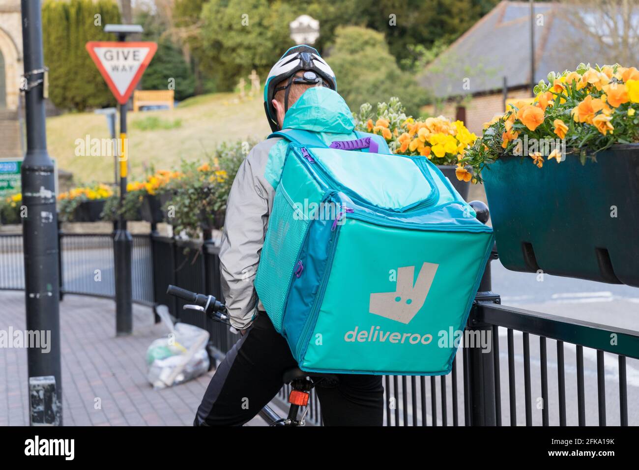 Deliveroo Biker vérifie son mobile pour la direction de l'adresse du client sur le pillage par les rails de fer avec panier de fleurs suspendu, Kent Banque D'Images