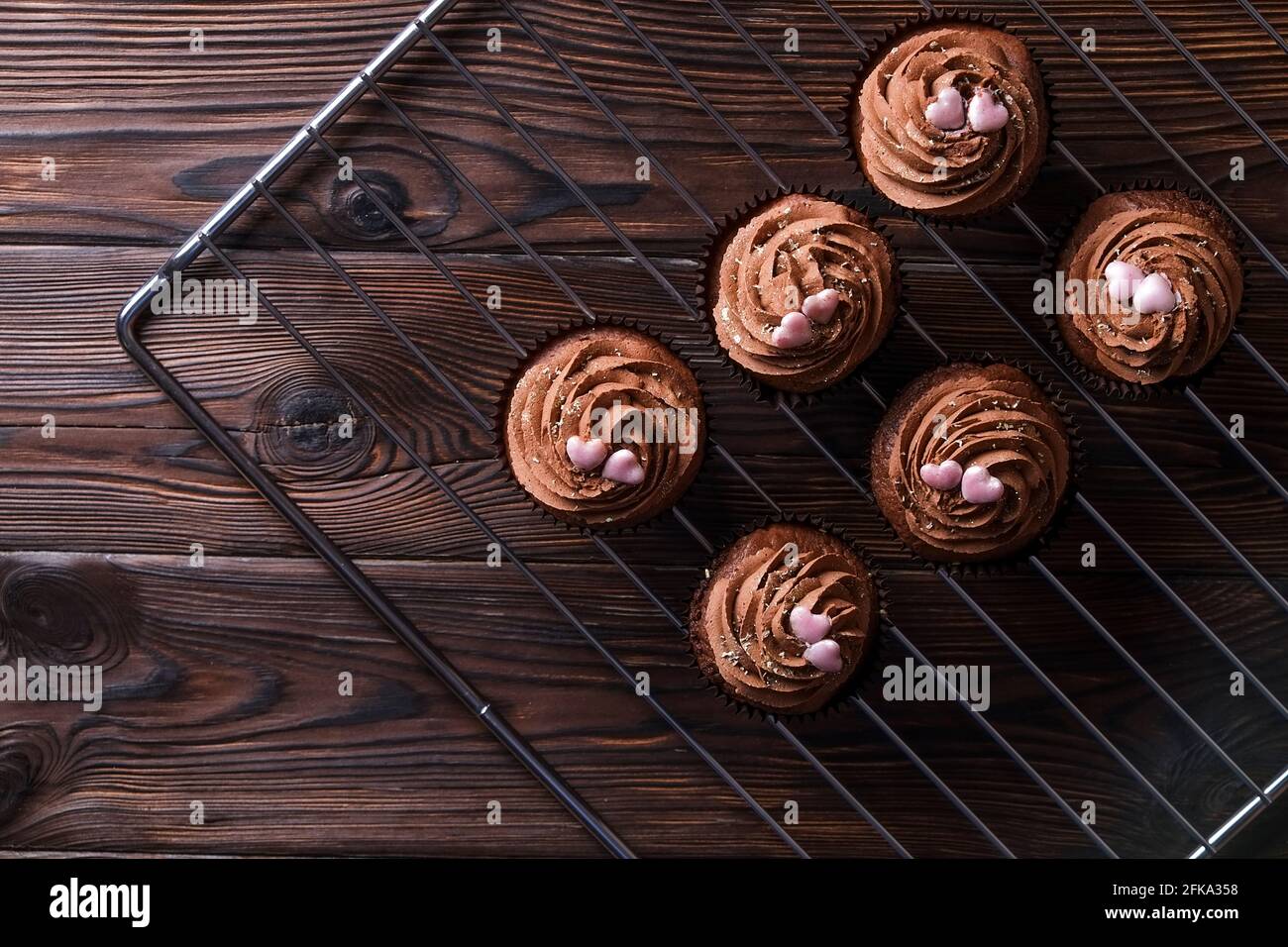 Délicieux cupcakes au chocolat noir, garniture en coeur de sucre, table texturée en bois. Boulangerie cacao, grille rustique étagère café-restaurant hippster table Banque D'Images