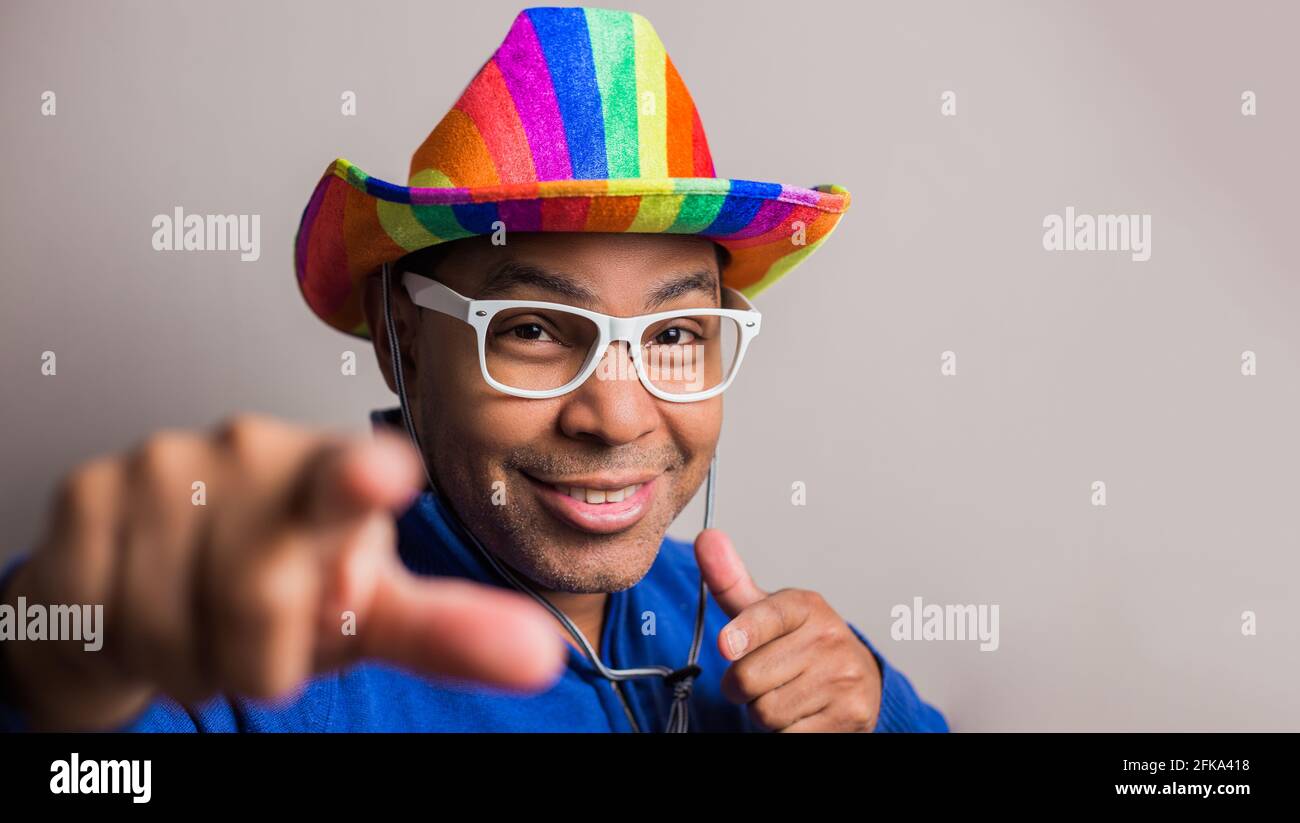 jeune homme aux cheveux foncés avec chapeau de drapeau lgbt et lunettes blanches Banque D'Images