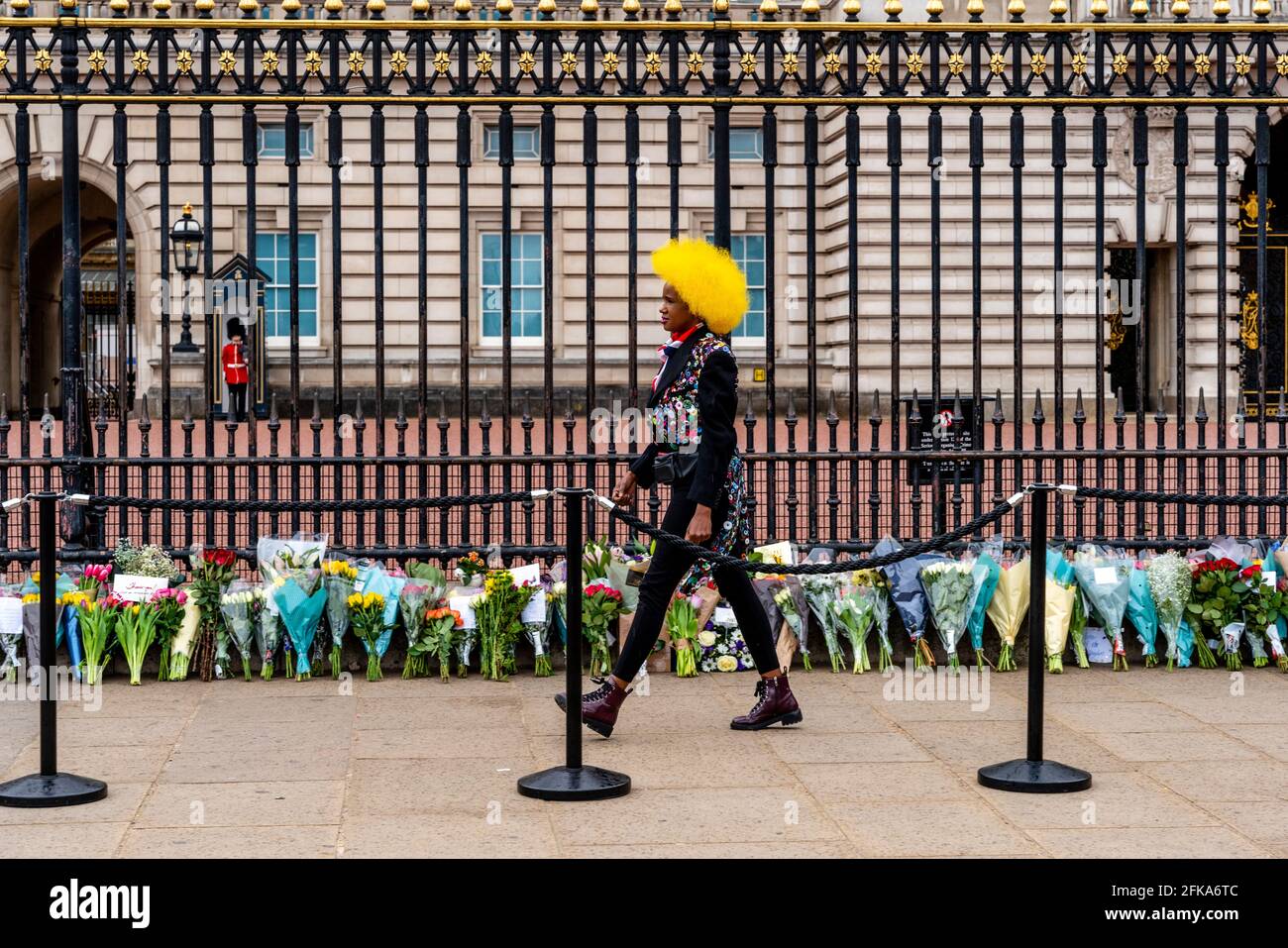 Une jeune femme britannique rend hommage au prince Philip qui est récemment décédé en posant des fleurs aux portes de Buckingham Palace, Londres, Royaume-Uni. Banque D'Images