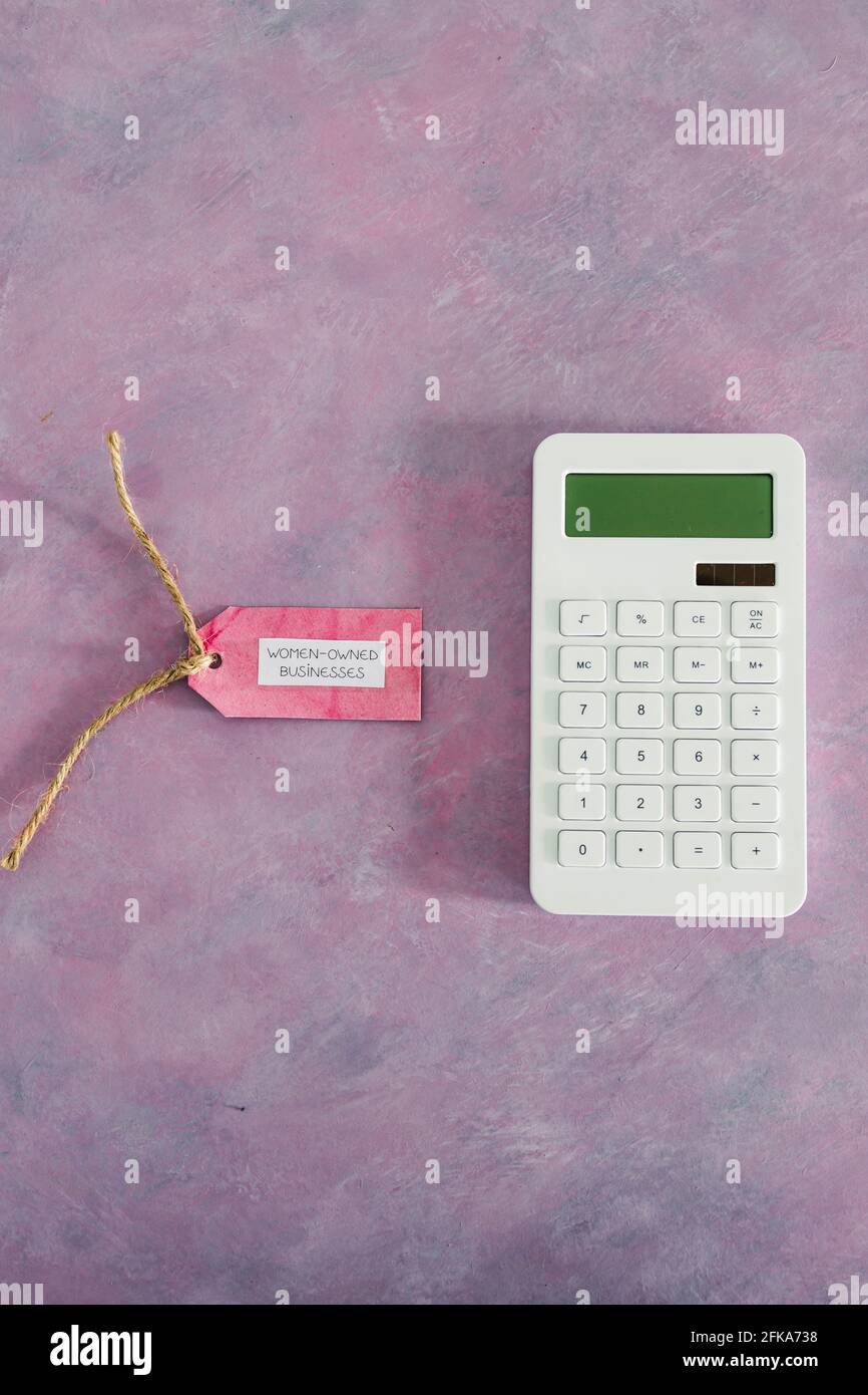 étiquette d'entreprise pour femmes avec calculatrice sur bureau rose, soutenant l'égalité et l'égalité des chances Banque D'Images