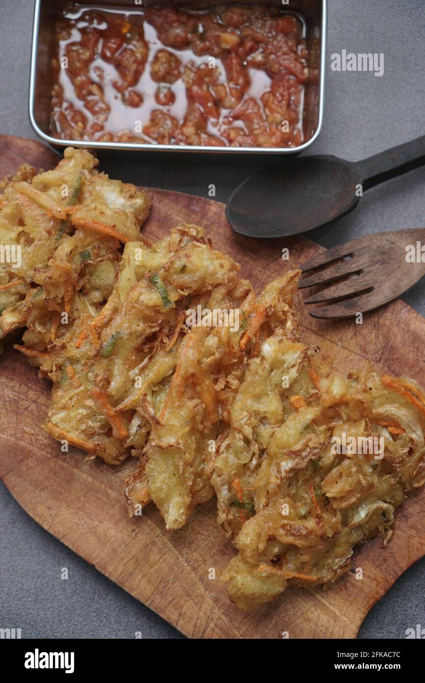 La collation traditionnelle est le bakwan frit avec une cuillère en bois et une fourchette sur fond gris. Banque D'Images