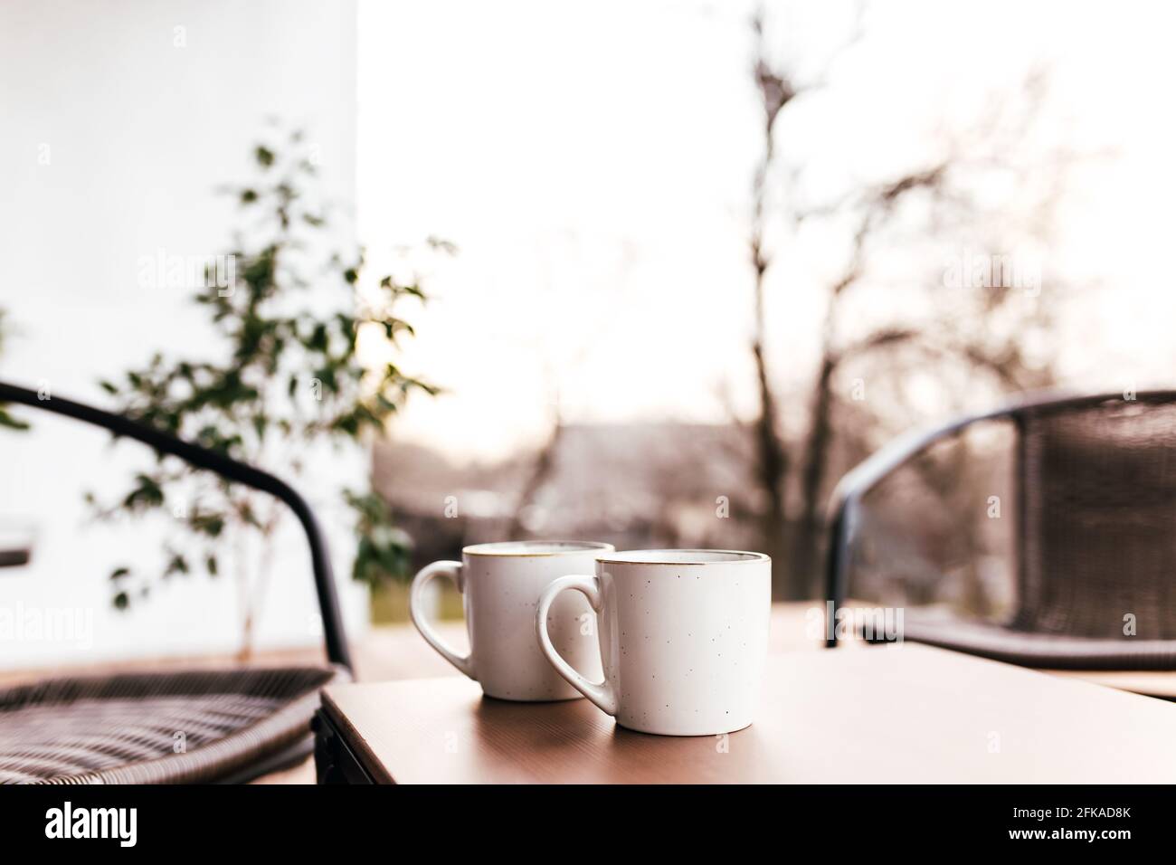 Deux tasses de café sur la table sur la terrasse en bois marron pendant le coucher du soleil avec un fond flou. Détente, concept de café ou de restaurant Banque D'Images