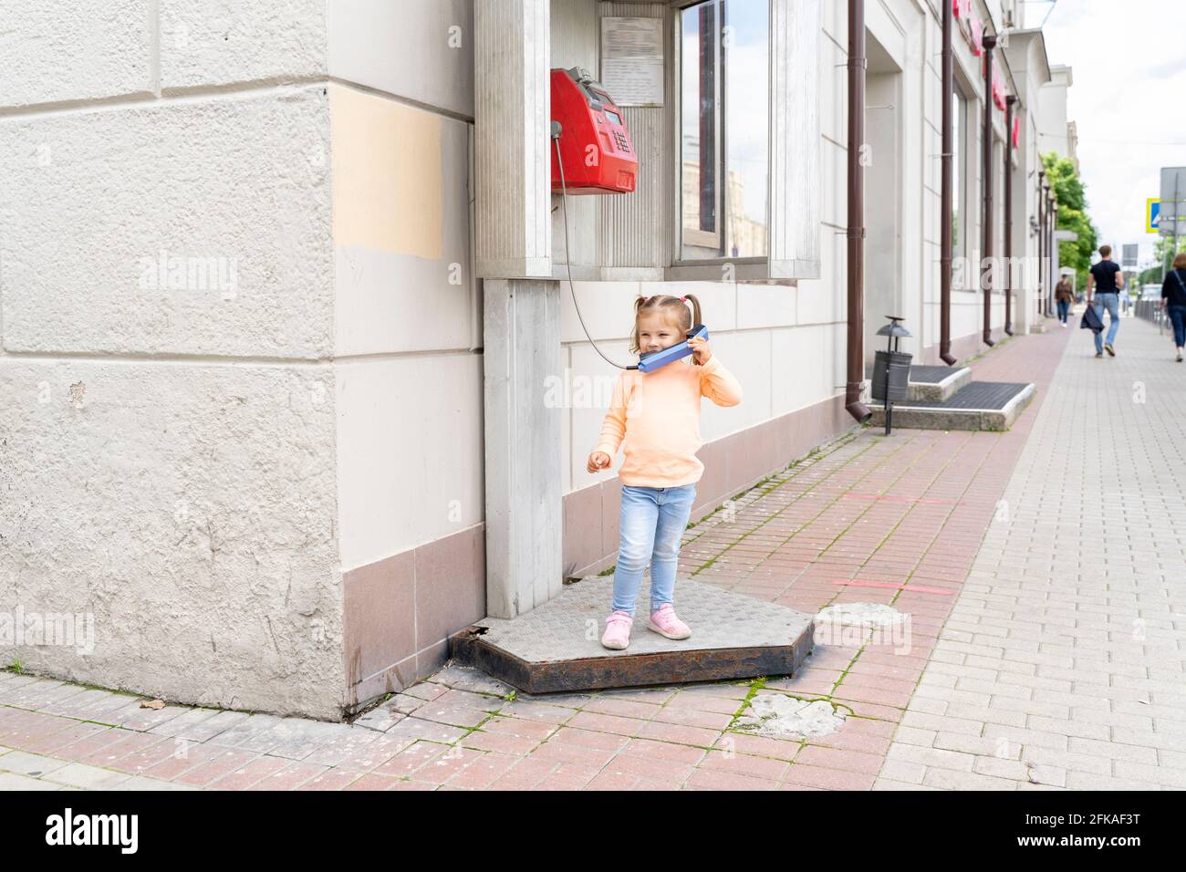 enfant à la cabine téléphonique de la ville. Banque D'Images