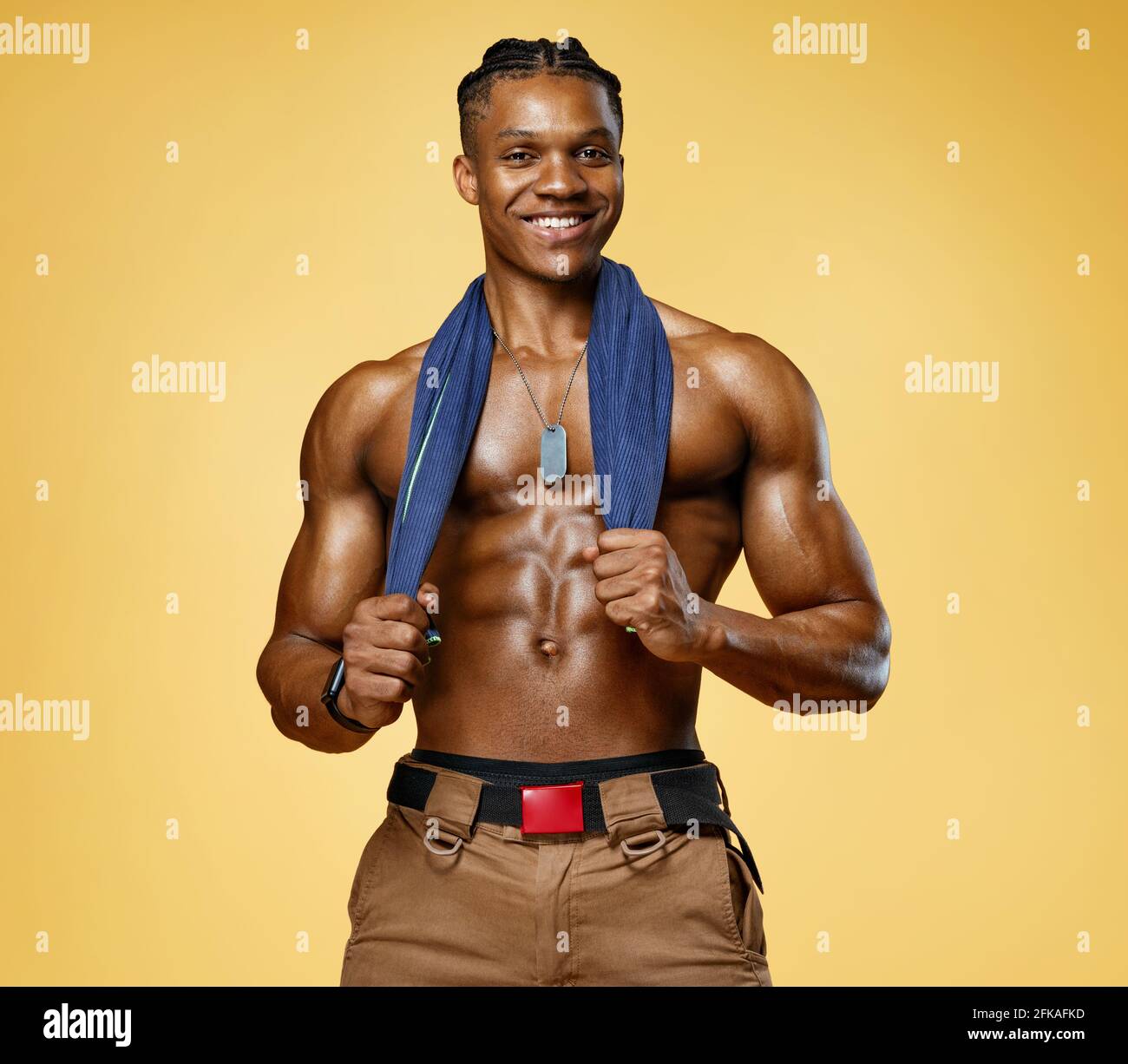 Homme souriant fatigué se reposant après l'entraînement. Photo d'homme sportif avec une serviette sur les épaules sur fond jaune. Temps de repos. Concept de santé. Banque D'Images