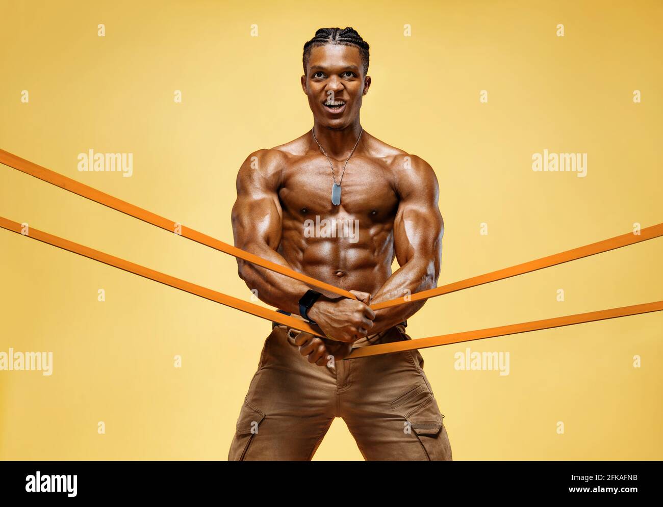 Homme fort travaillant avec la bande de résistance. Photo d'un homme avec un corps sportif sur fond jaune. Force et motivation Banque D'Images
